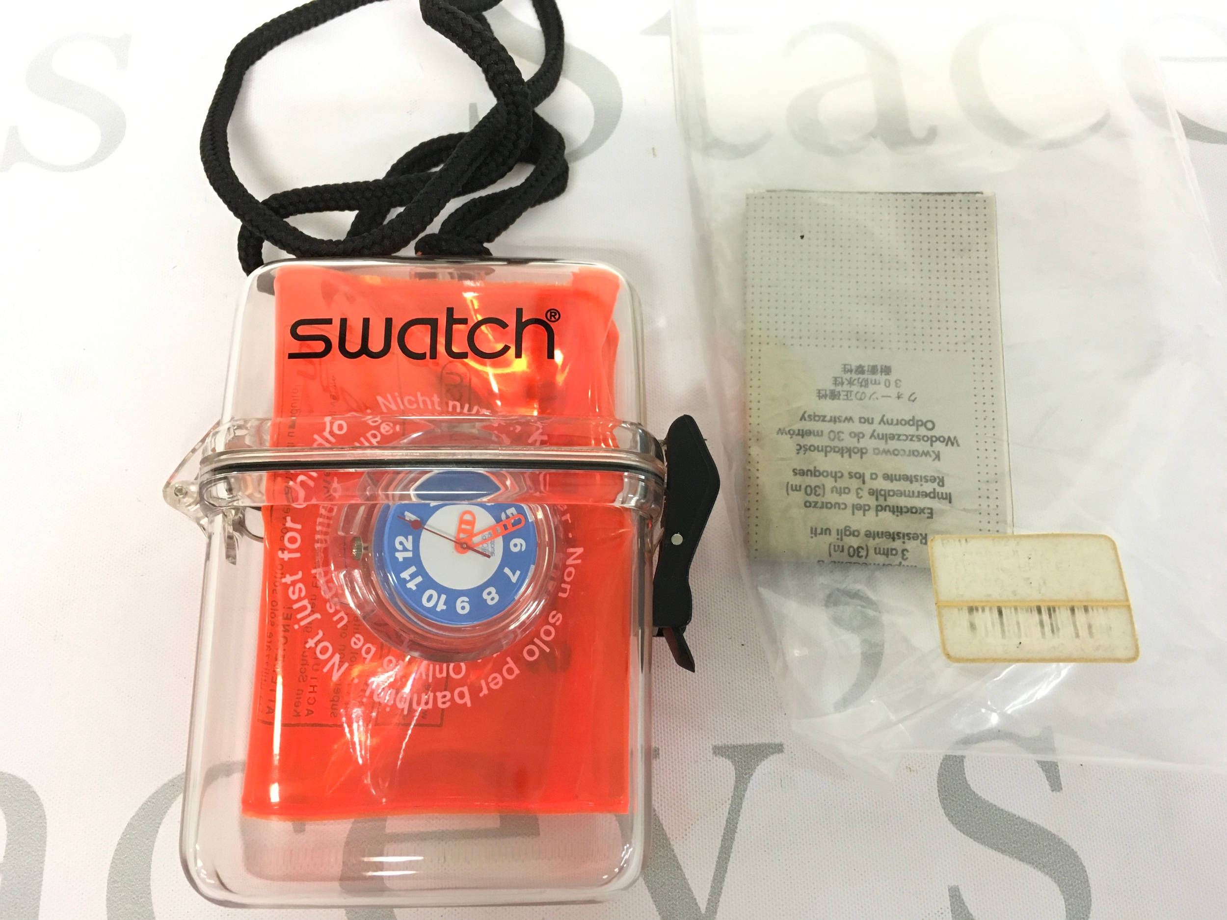 Swatch "Aquafun" (PMK122) Pop watch from 1998, packaged inside a clear, inflatable plastic arm float. The watch features a blue, white, and red dial design with white numbers, emphasizing the themed "Pop" series concept. It comes in a special clear plexiglass case, designed to house both the watch and its unique inflatable accessory