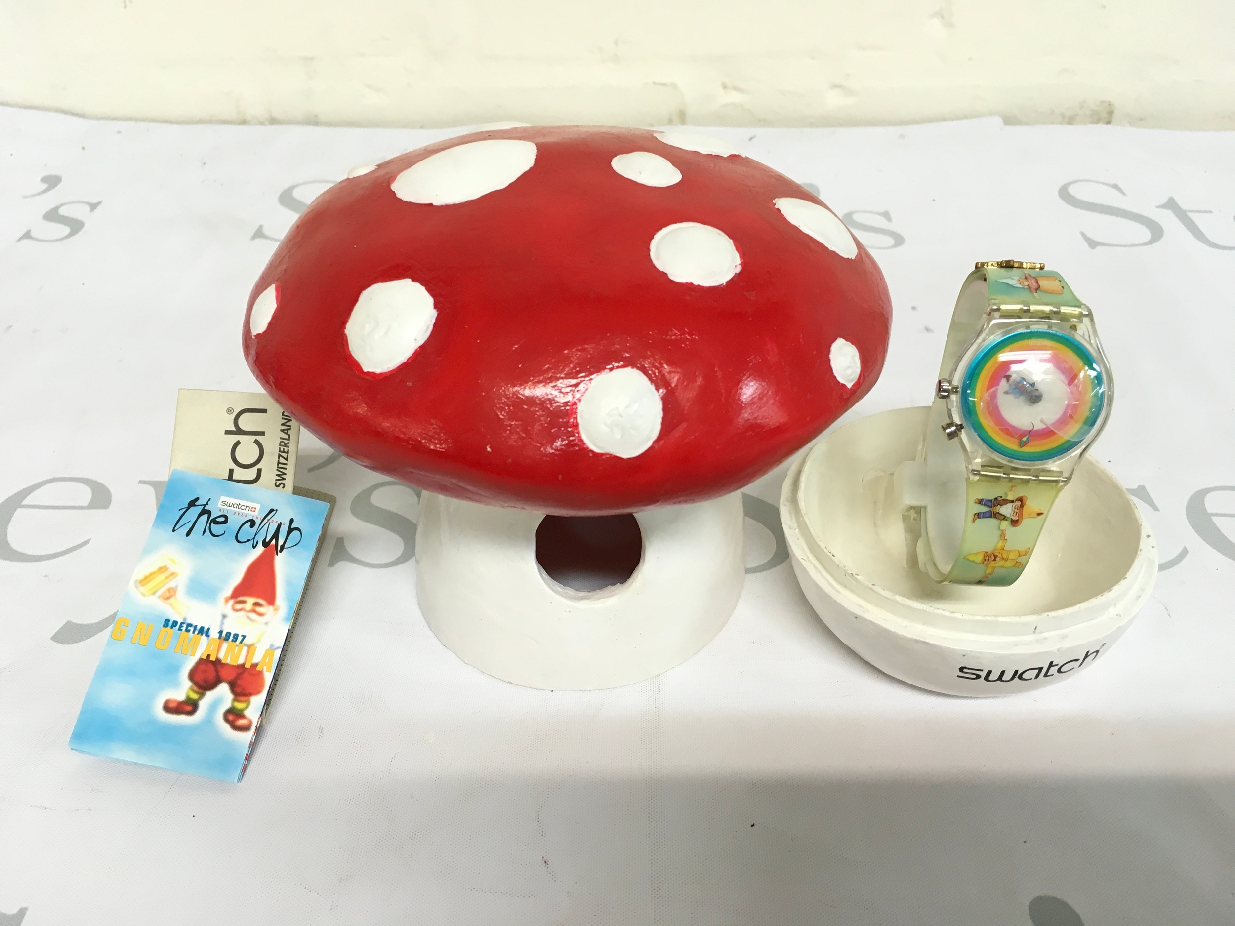 Swatch Gent Club Special "Gnomania" (GZ901) watch, released in 1997 for club members and limited to 19,999 pieces. The watch features a unique "Loomi" light function activated by a button press. It comes with special packaging designed to look like a red and white mushroom or toadstool.