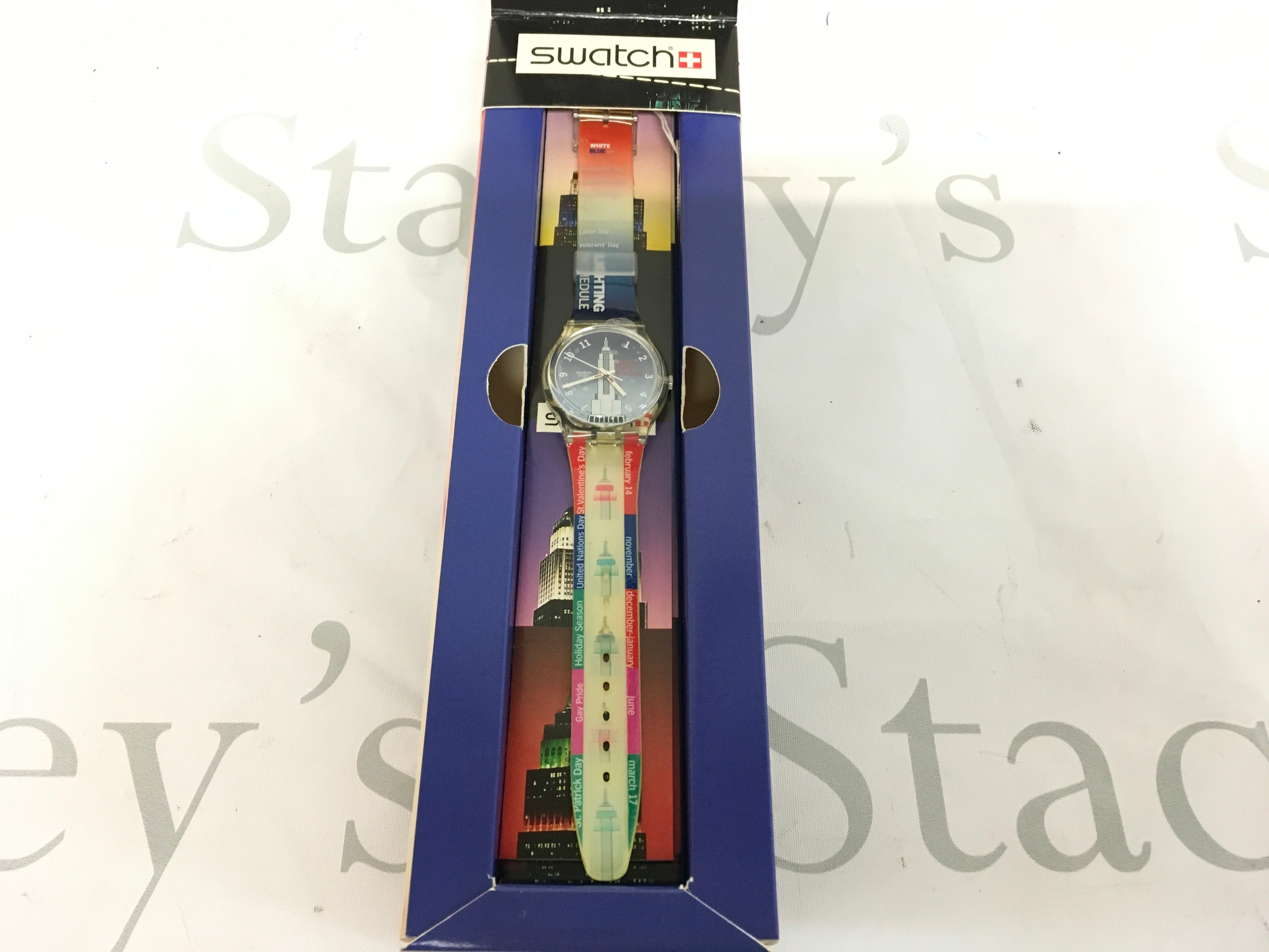 1999 Swatch Gent watch named "Empire State Building" (model GK309). It features a colorful strap showcasing New York City themes and a dial depicting the Empire State Building against a blue sky.