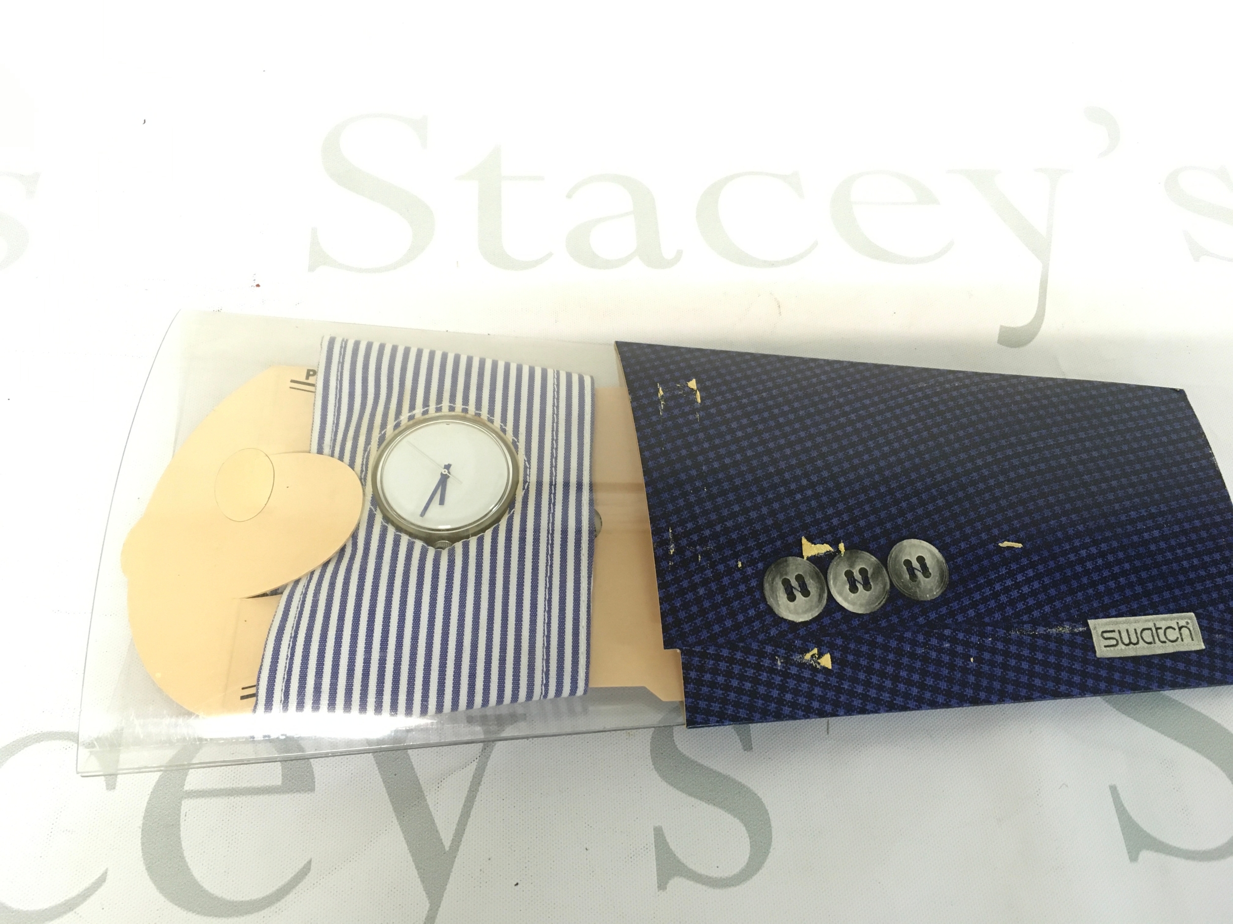 Swatch branded item features a unique blue and white micro-check pattern reminiscent of a dress shirt cuff.
