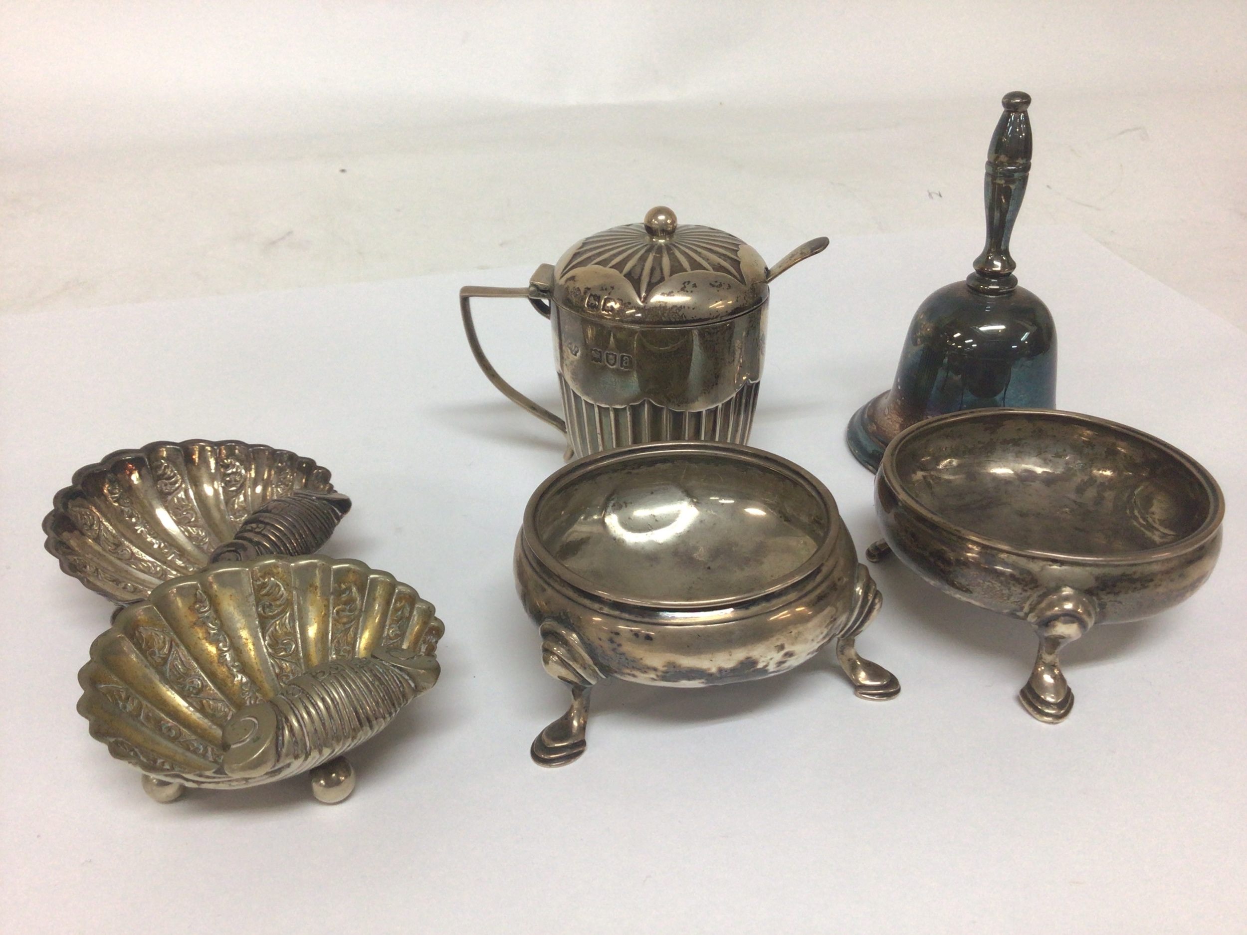  A Pair of of George II 1757 silver Salt cellars London hallmarks a silver mustard pot with a blue glass liner and hinged lid and other oddments a pair of shell shaped salt cellars and a small table bell 