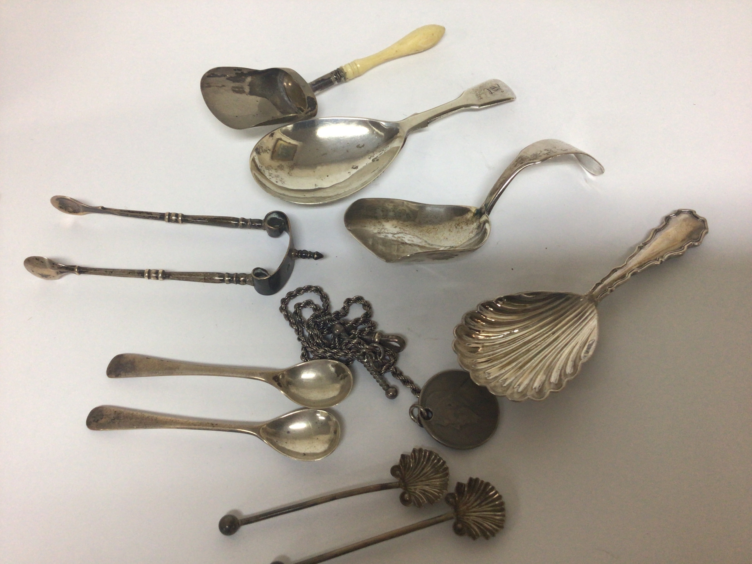  A Collection of four George III and later silver tea caddy spoons silver sugar nips and spoons and a silver chain. 