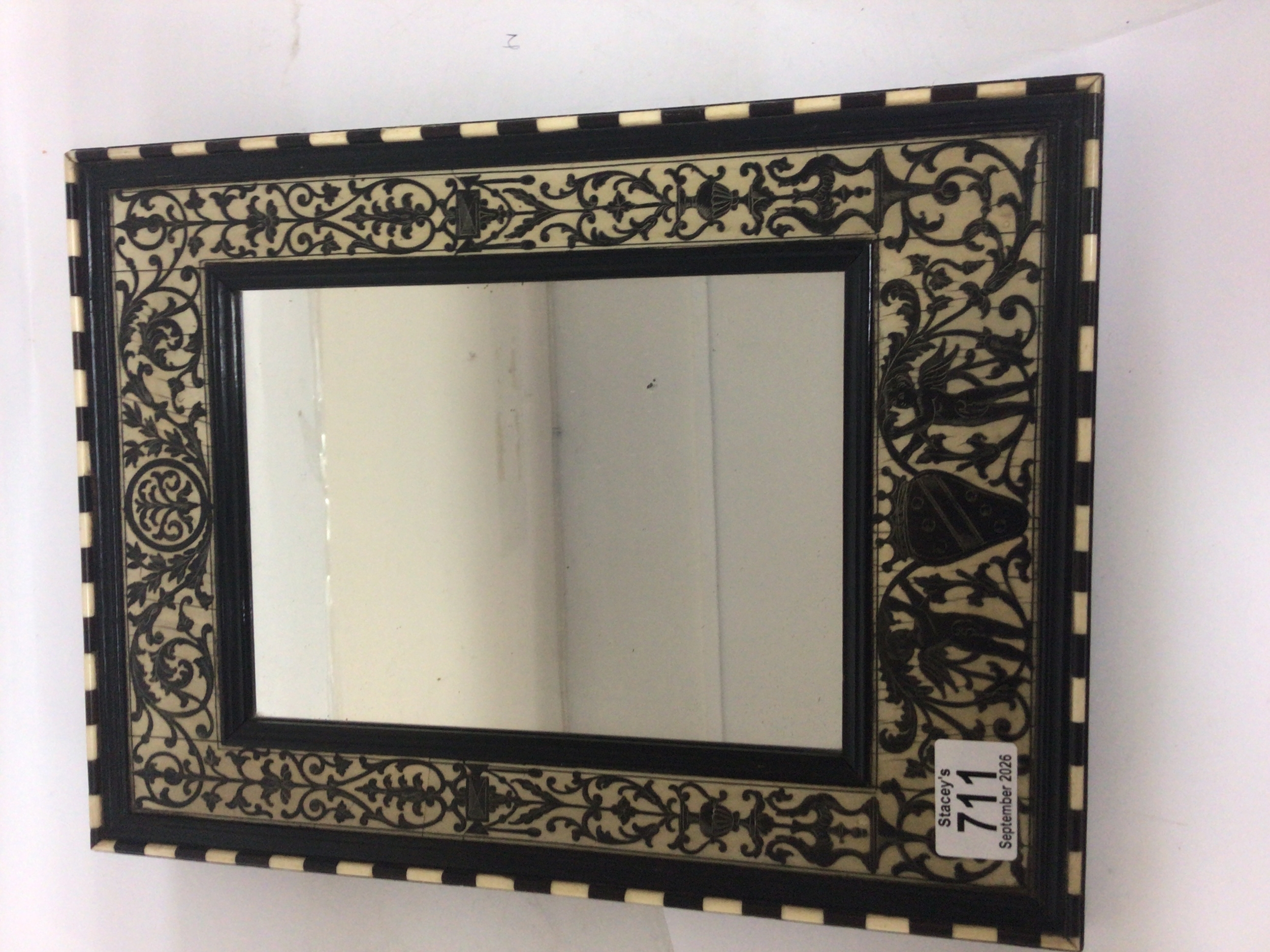  A 19th ebony veneered wall mirror of rectangular shape with a Neo-Classical design with scrolls and cherubs. 27x36cm 
