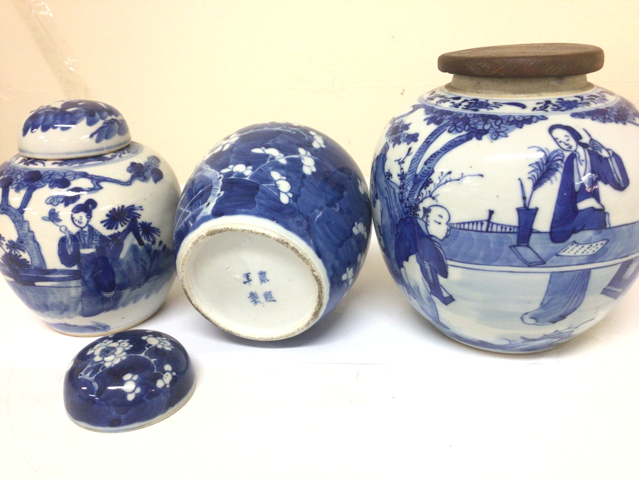 Three Chinese blue and white early 19th century Export porcelain ginger jars two with ceramic covers marks to the base Kangxi mark one with chips to the rim. Maximum Height 19cm. 