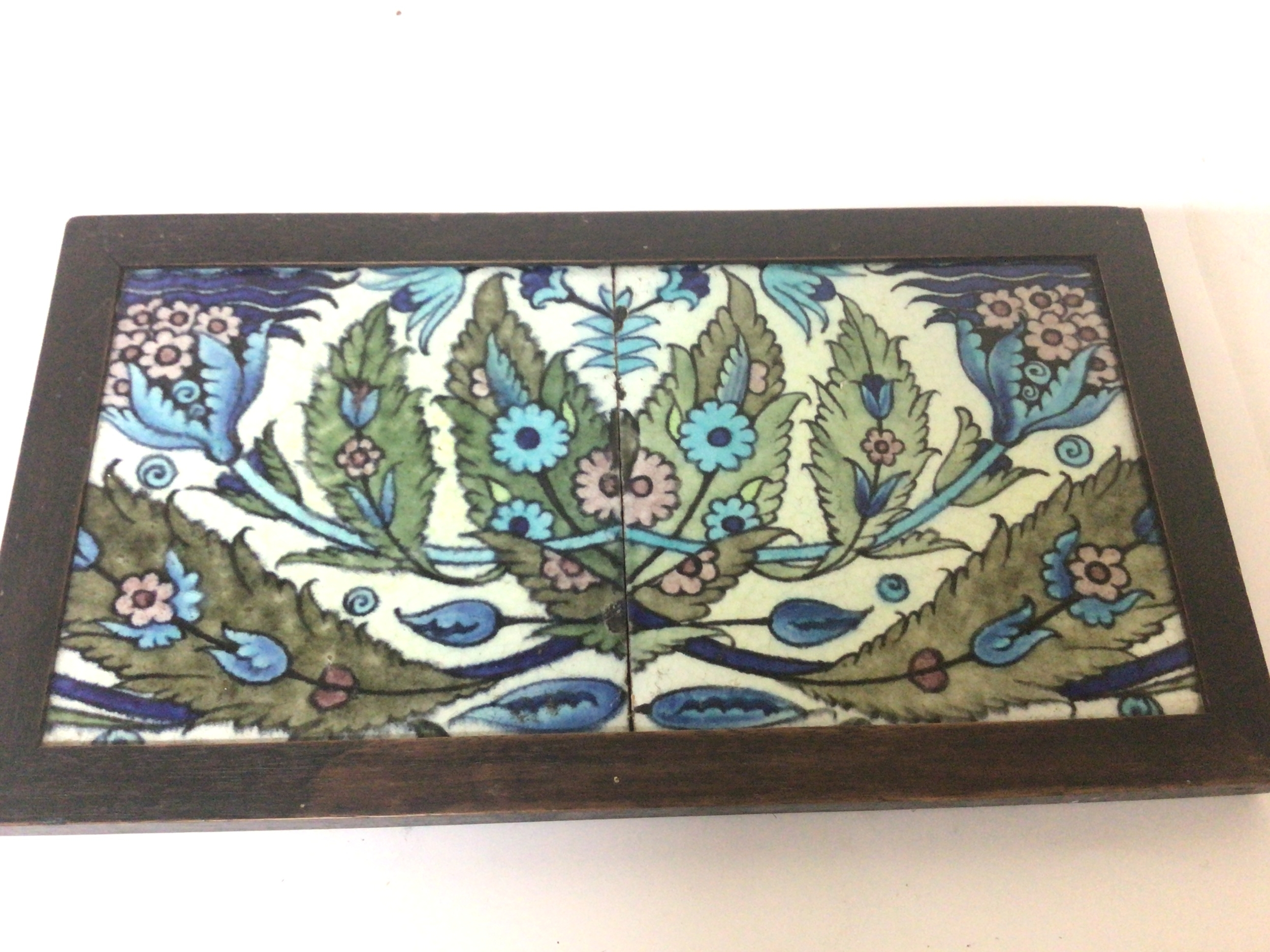 A Victorian Arts and Crafts William de Morgan double polychrome tile with a floral pattern set in a sealed wood frame. 34x18cm 