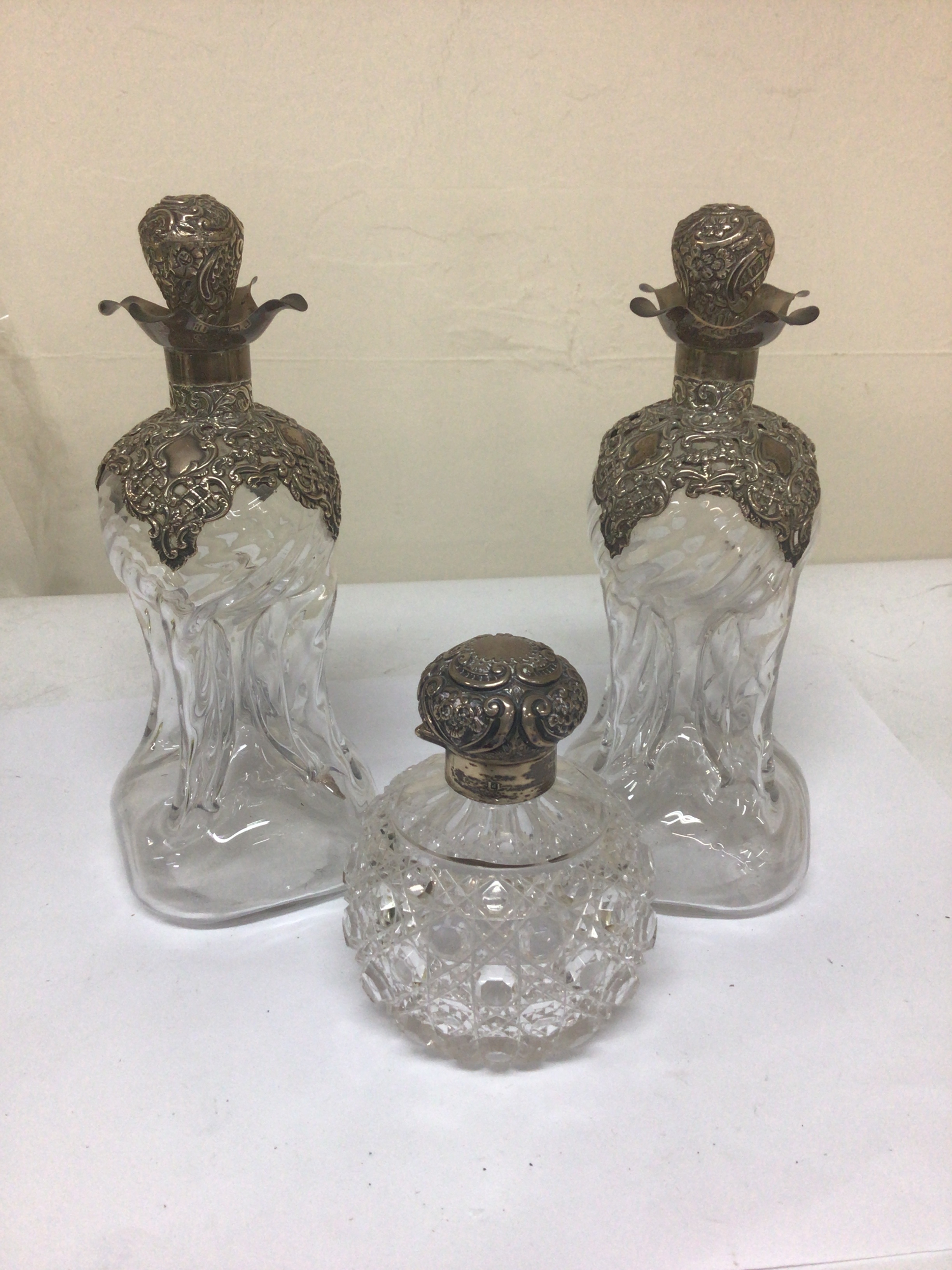 A pair of quality silver and glass decanters Birmingham 1900 with detachable stoppers no obvious damage Hight 22cm and a silver and glass scent bottle with a hinged lid (3) 