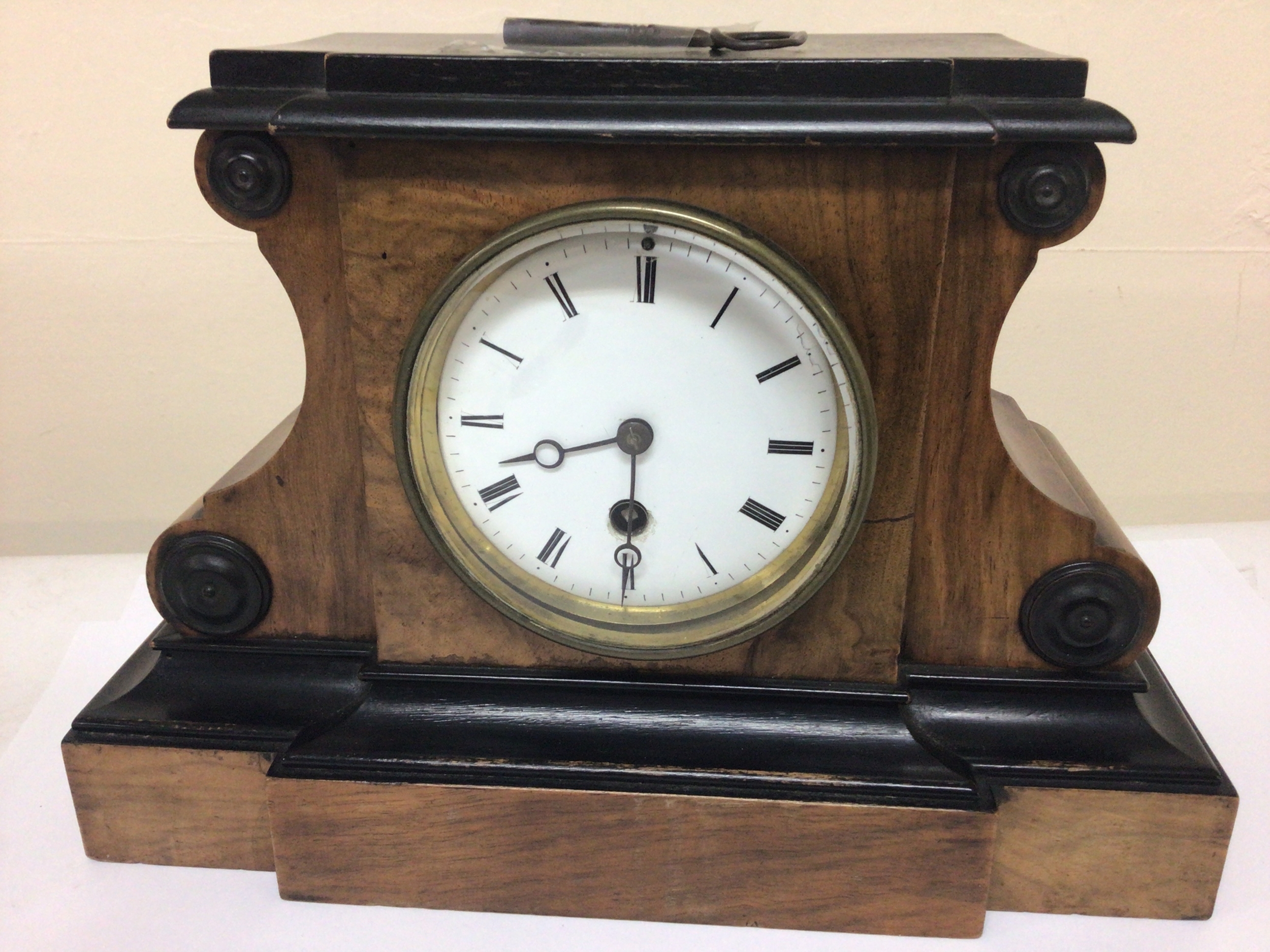  A Victorian walnut and ebonized mantle clock with an enamel dial. brass French movement with key and pendulum. Hight 21cm 
