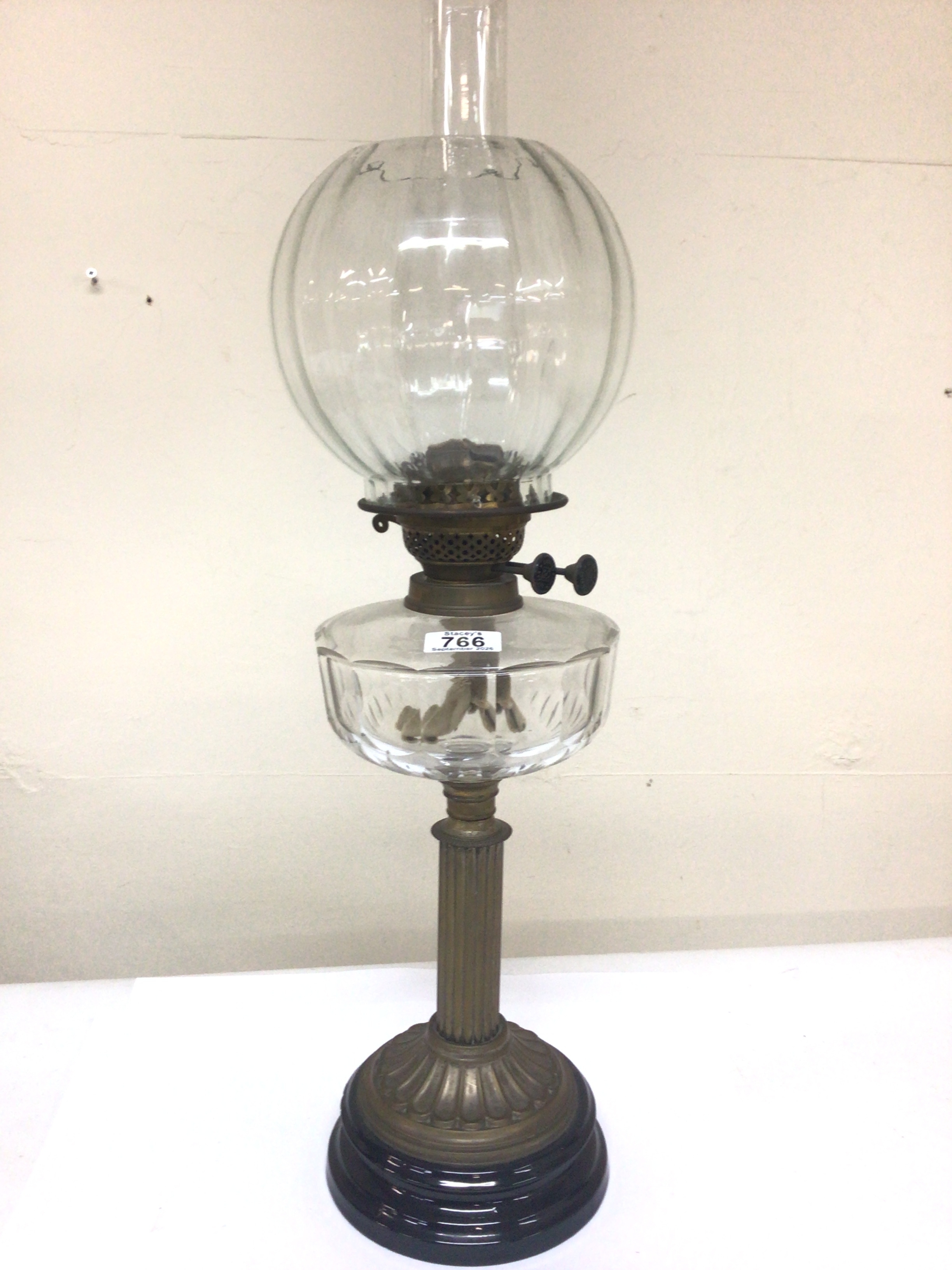 A Victorian oil lamp with a glass reservoir shade and chimney brass fluted column no obvious damage Hight 66cm.
