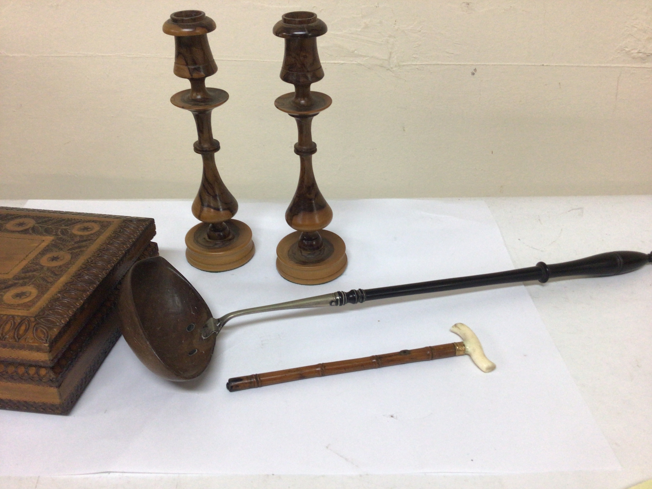  A pair of turned Olive-wood treen candle sticks a miniature walking cane a carved box and an unusual ebony and nut shell toddy ladle and a carved wood box 