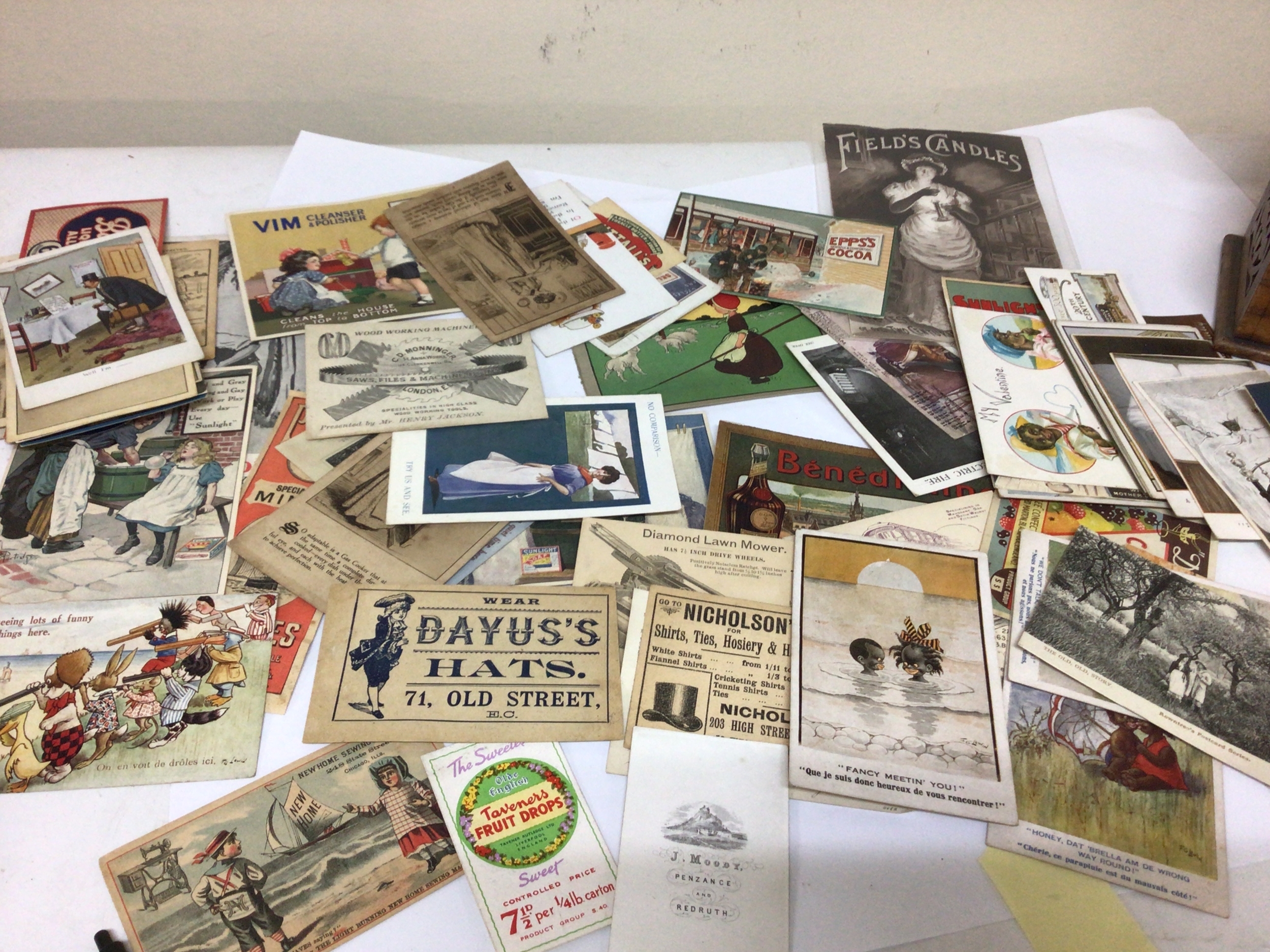  A box containing vintage commercial postcards and Victorian and later trade cards. 