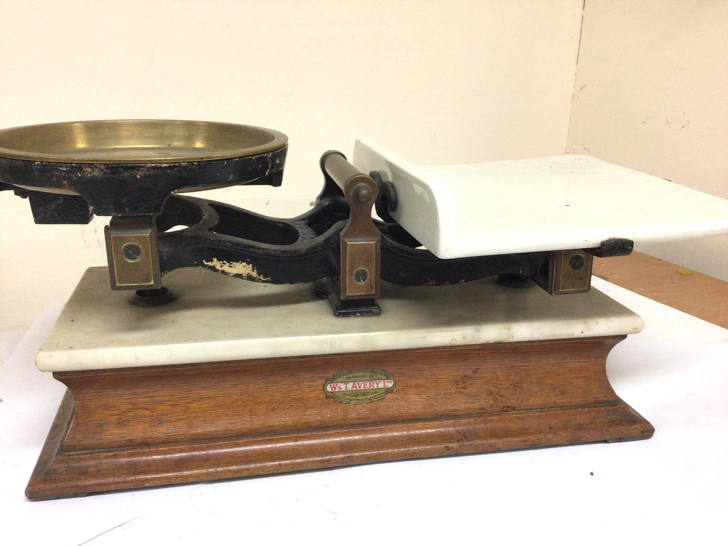  A set of shop beam balance scales with a solid brass pan ceramic slab on marble and oak base maker W&T Avery Ltd. With some weights. 