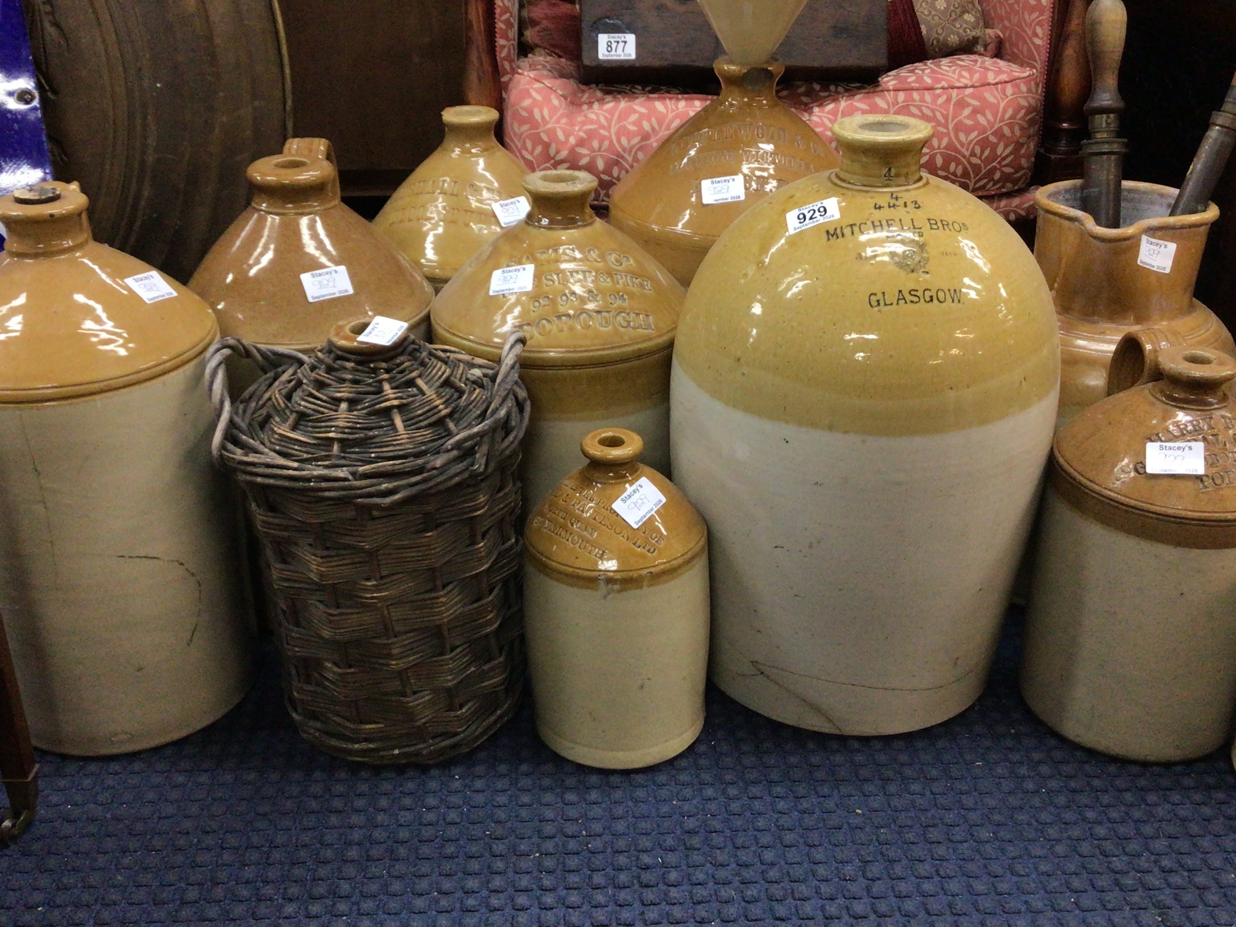  An Extensive collection of stoneware flagons and large storage vessels mainly late 19th century Gin and other liquid many impressed with regional brewers and makers stamps a stoneware funnel and kitchen implements 