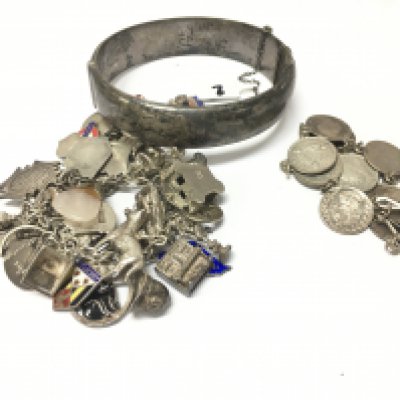 A collection of silver jewellery including charm and coin bracelets and a bangle. Approx weight 120 grams.