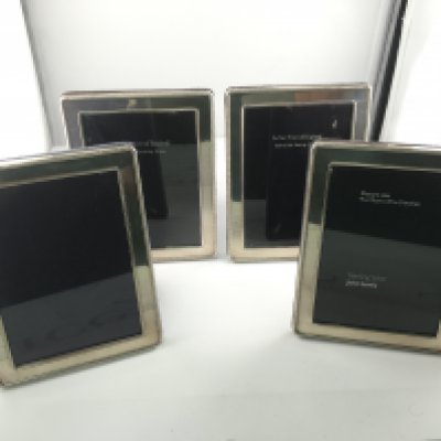 Four silver hallmarked photo frames. Approximately 12cm by 16cm.