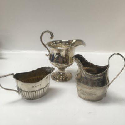 Three silver jugs, two George III jugs and one Victorian cream jug. Approx weight 303 grams.