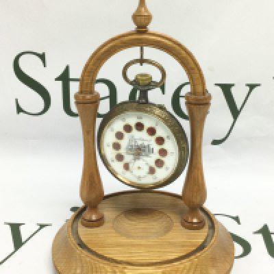 Railway interest. An oversized French brass and base metal pocket watch with decorative enamel roundels and an image of a steam train to the dial. Comes with a turned wood watch stand. Shipping category B.