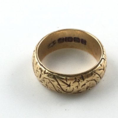 An 18ct gold wedding band with decorative engraving. 10.27g and size NPostage A