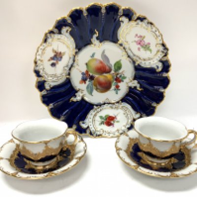 A Meissen porcelain cabinet plate with hand painted floral and fruit design, together with two gilt and royal blue Meissen cups and saucers. (D)