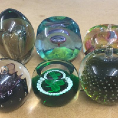 A collection of six glass paper weighs.