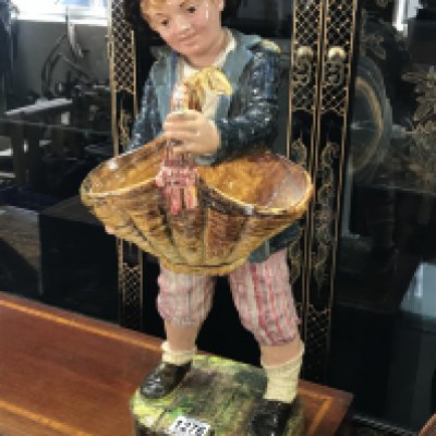 A large ceramic figure of a boy holing a basket. 50cm