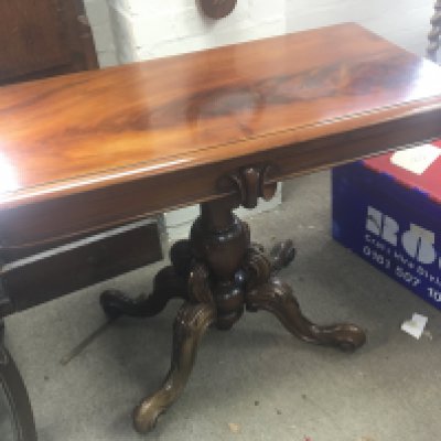 A Victorian mahogany card table with a hinged top on a bulbous column and splayed legs.