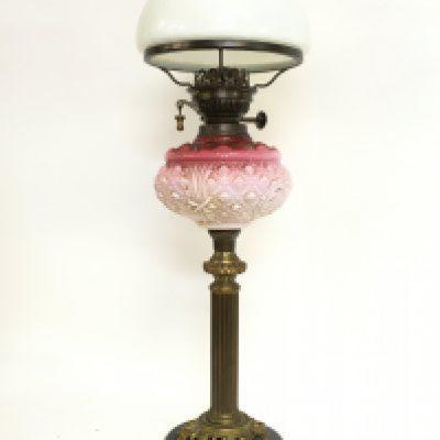 A late 19th century brass oil lamp with pink glass and a milk glass shade, approximately 67cm tall. This lot cannot be posted