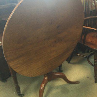 A Georgian mahogany tilt top occasion table the circular top above a turned column on splayed legs .