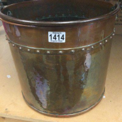 A copper bucket with swing handle .