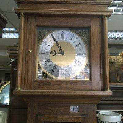 An oak long cased clock with a brass dial and visible weights