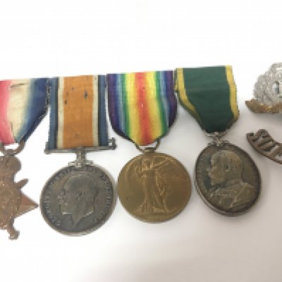 A Group of four First World War Medals awarded to 93. Pte.H Sizer Suffolk Regiment with cap badge and one shoulder badge the group of medals including Territorial Efficiency Medal
