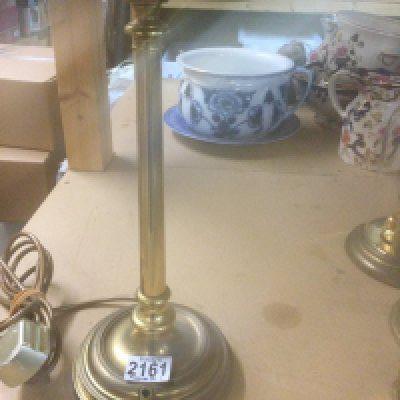 A brass students lamp with green shade .