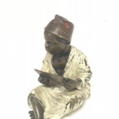 A hand painted late 19th century Austrian Bergman bronze in the form of a seated Middle Eastern boy holding a script. Height 8cm