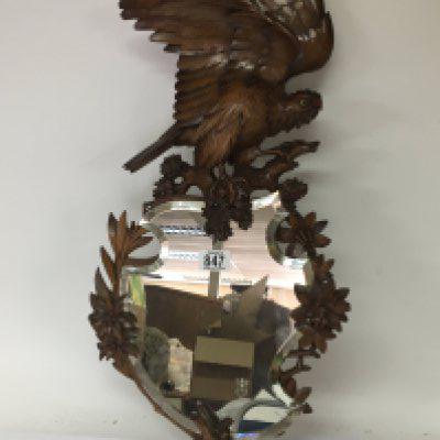 A Quality Black Forest carved wood mirror the top with a bird of prey with glass eyes with a shaped mirror with raised carved flowers and foliage height 73cm