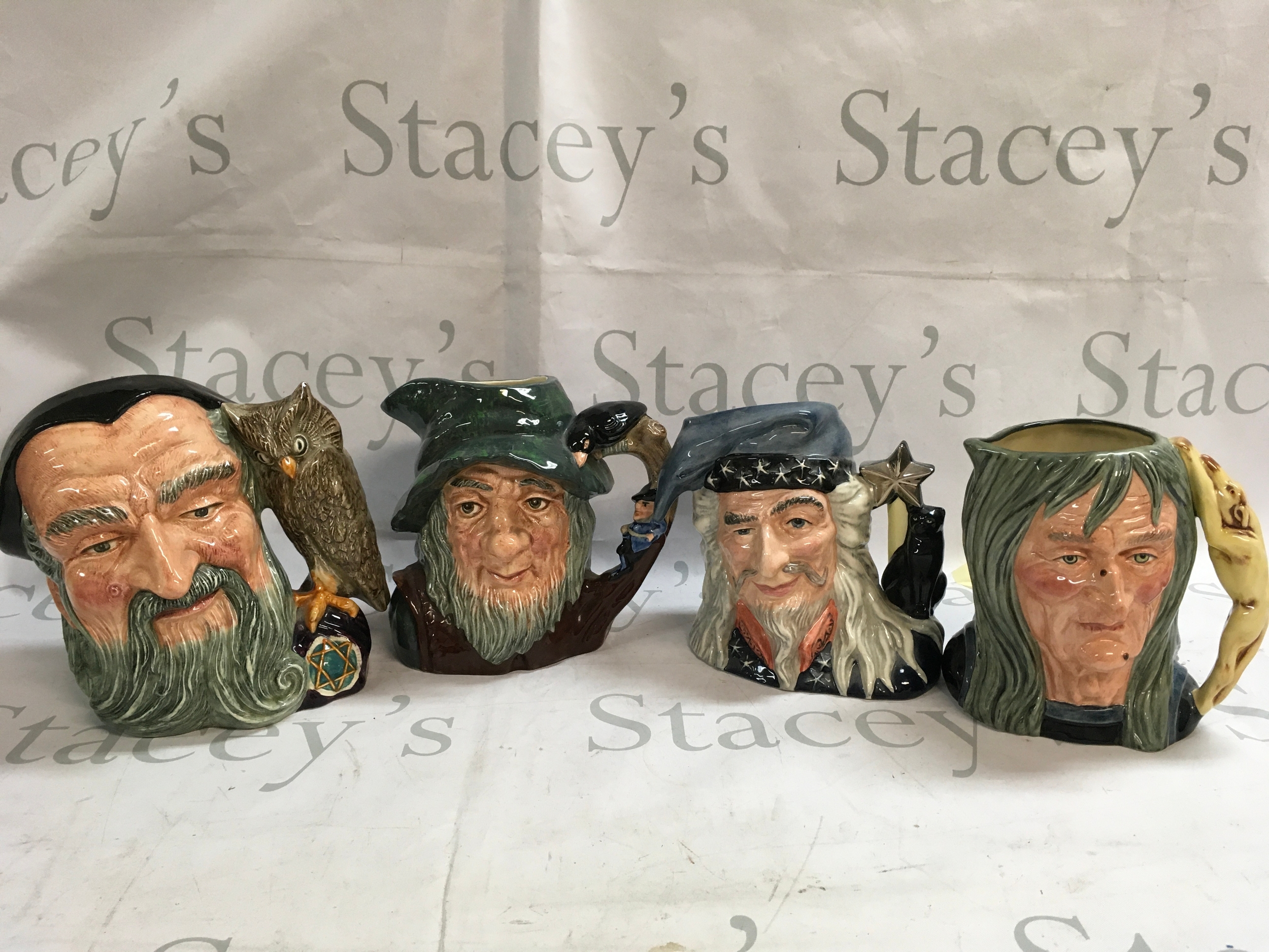 A collection of four Doulton character jugs including Rip Van Winkle, The Wizard, The Pendle Witch, and Merlin. 