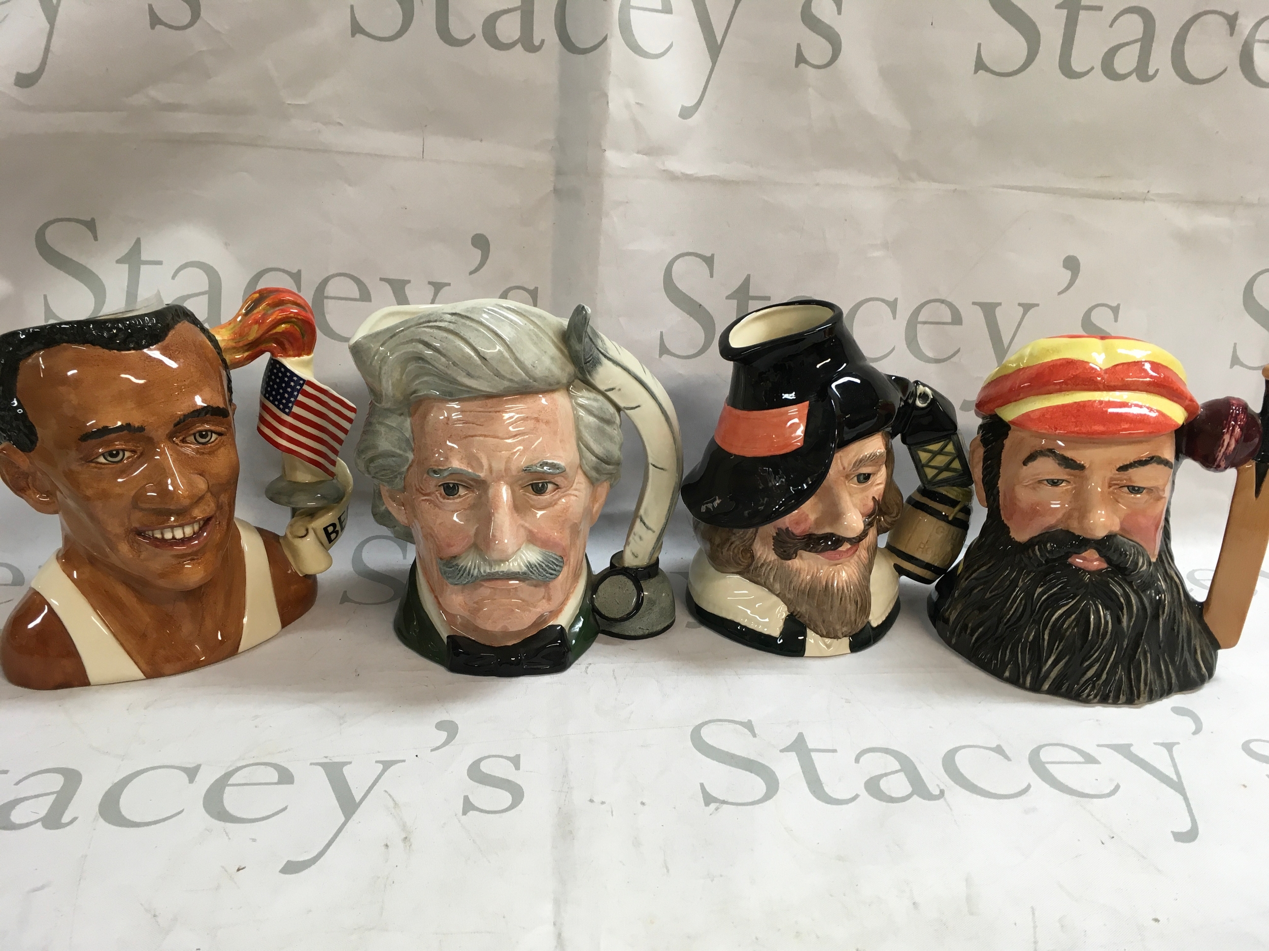 A collection of 4 Doulton character jugs including Jesse Owens, Mark Twain, Guy Fawkes, W.G. Grace. 
