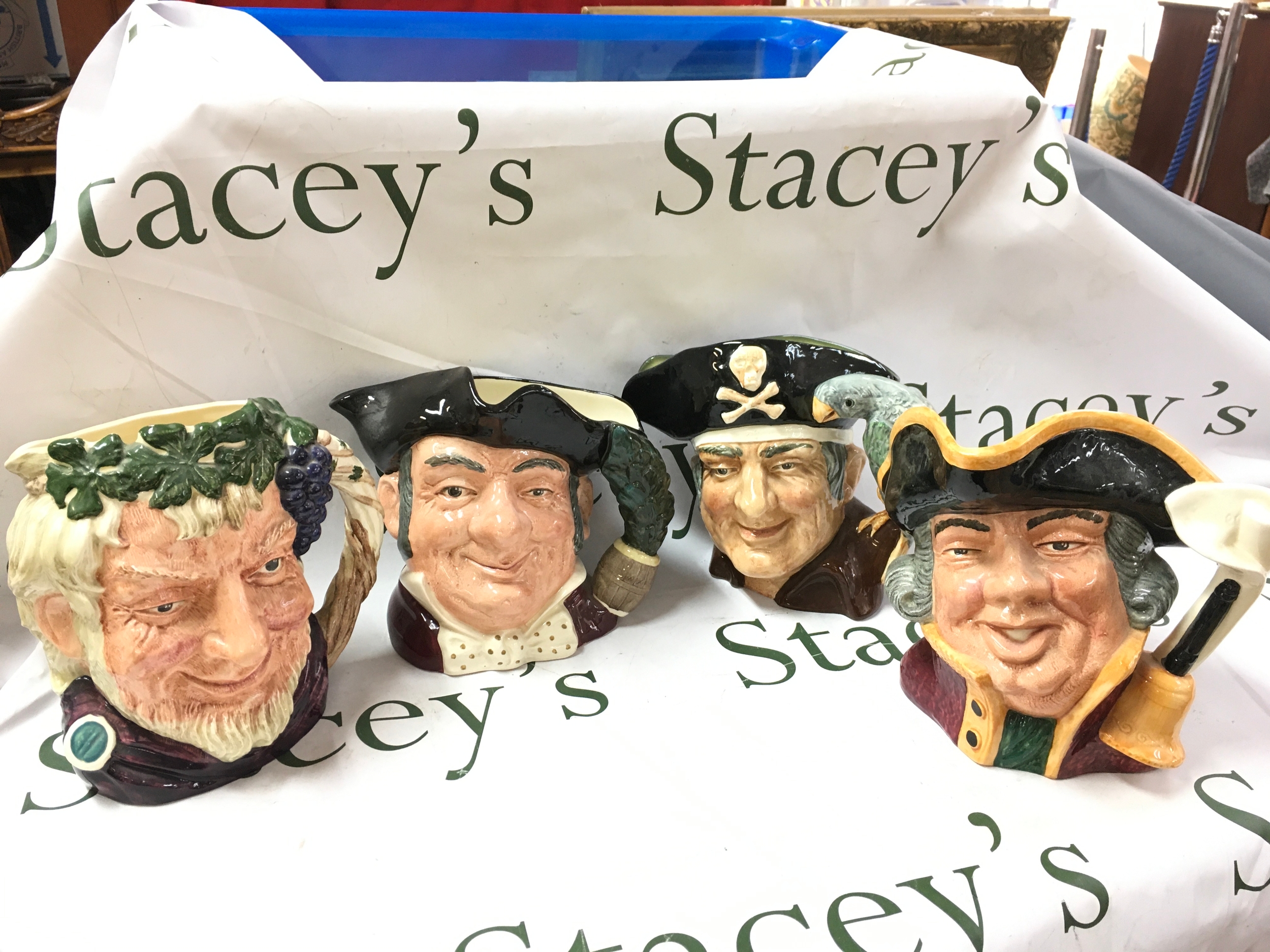 Four Royal Doulton character jugs Town Crier D6530, Long John Silver D6335, Mine Host D6468, Bacchus D6499. No obvious damage or restoration
