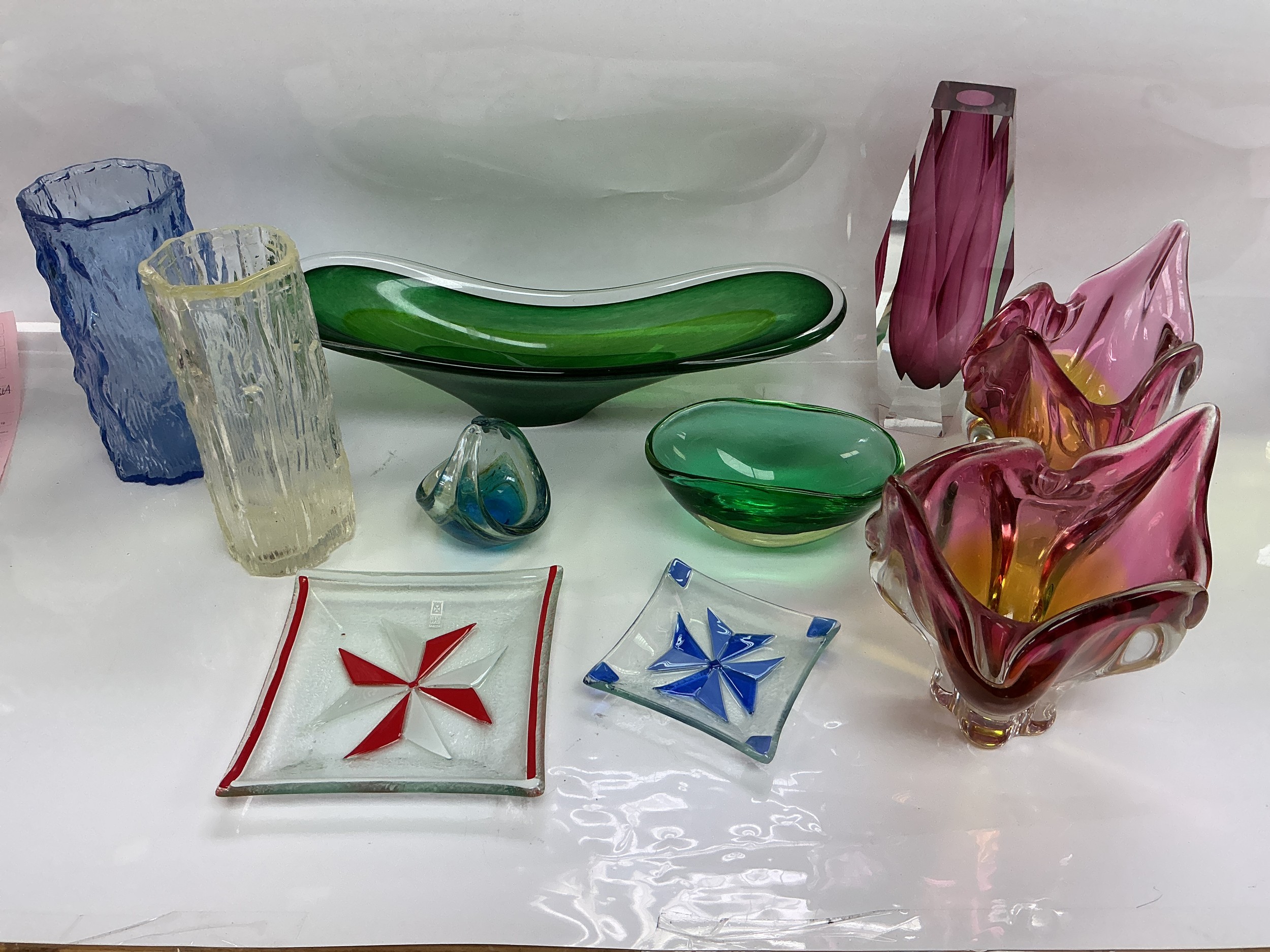 A collection of coloured glassware including Mdina examples.