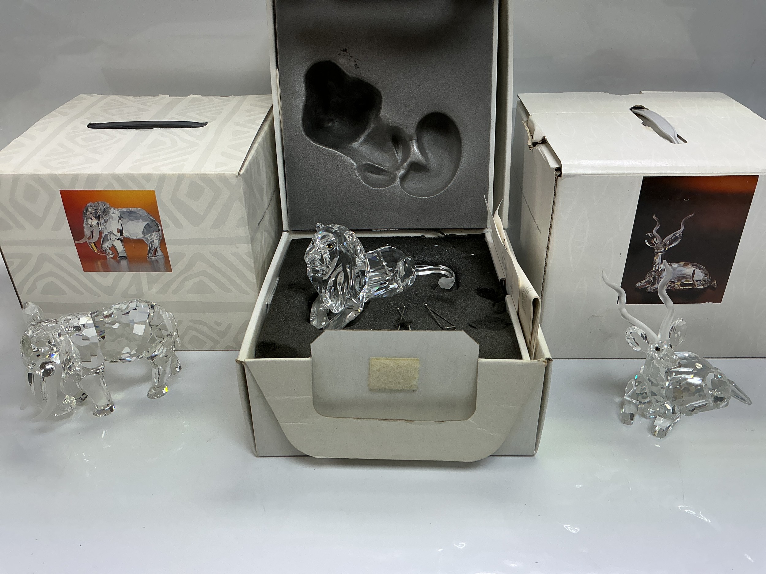 Three boxed Swarovski figures of animals comprising a lion, elephant and a Kudu.
