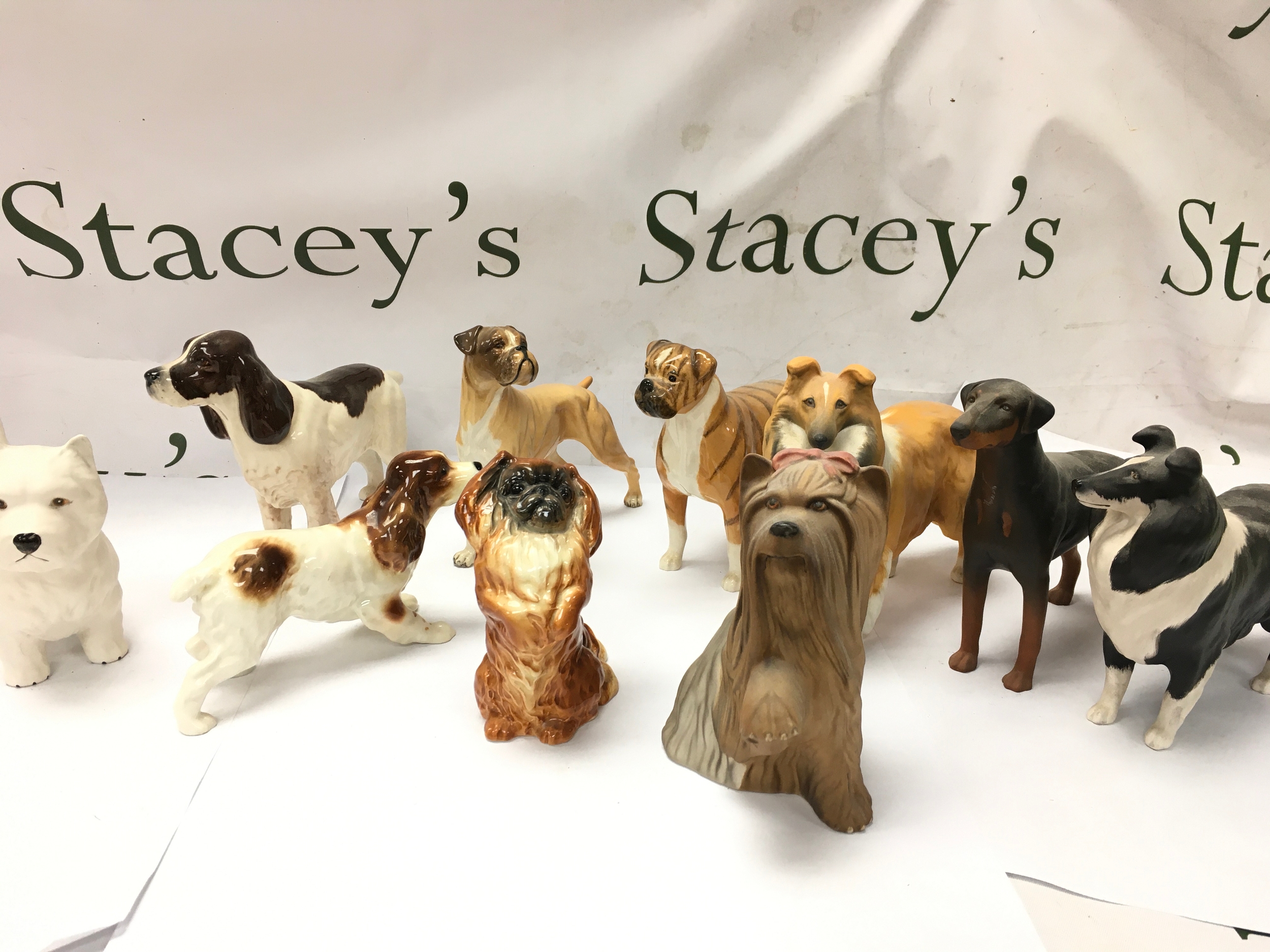 vintage ceramic and porcelain dog figurines, including breeds such as a West Highland Terrier, Cocker Spaniel, Boxer, Collie, Yorkshire Terrier, Doberman, and others By makers like beswick etc.