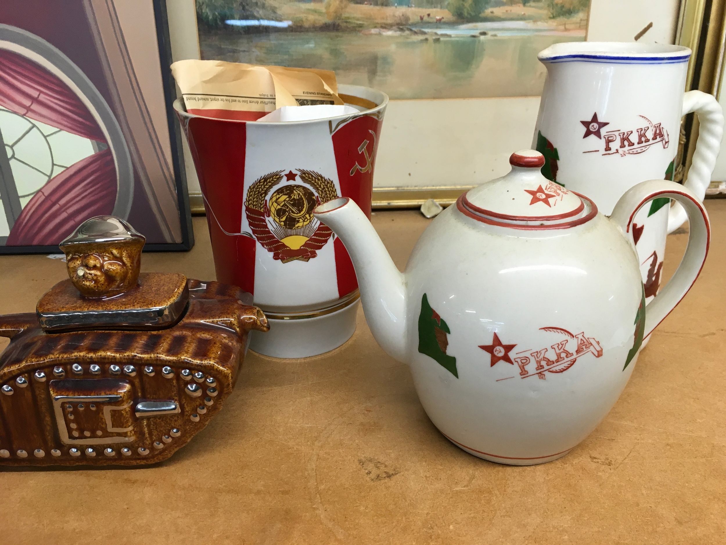 vintage Soviet porcelain teawares including a white porcelain teapot featuring the red star and ???? (Workers' and Peasants' Red Army), alongside a tank-shaped novelty teapot