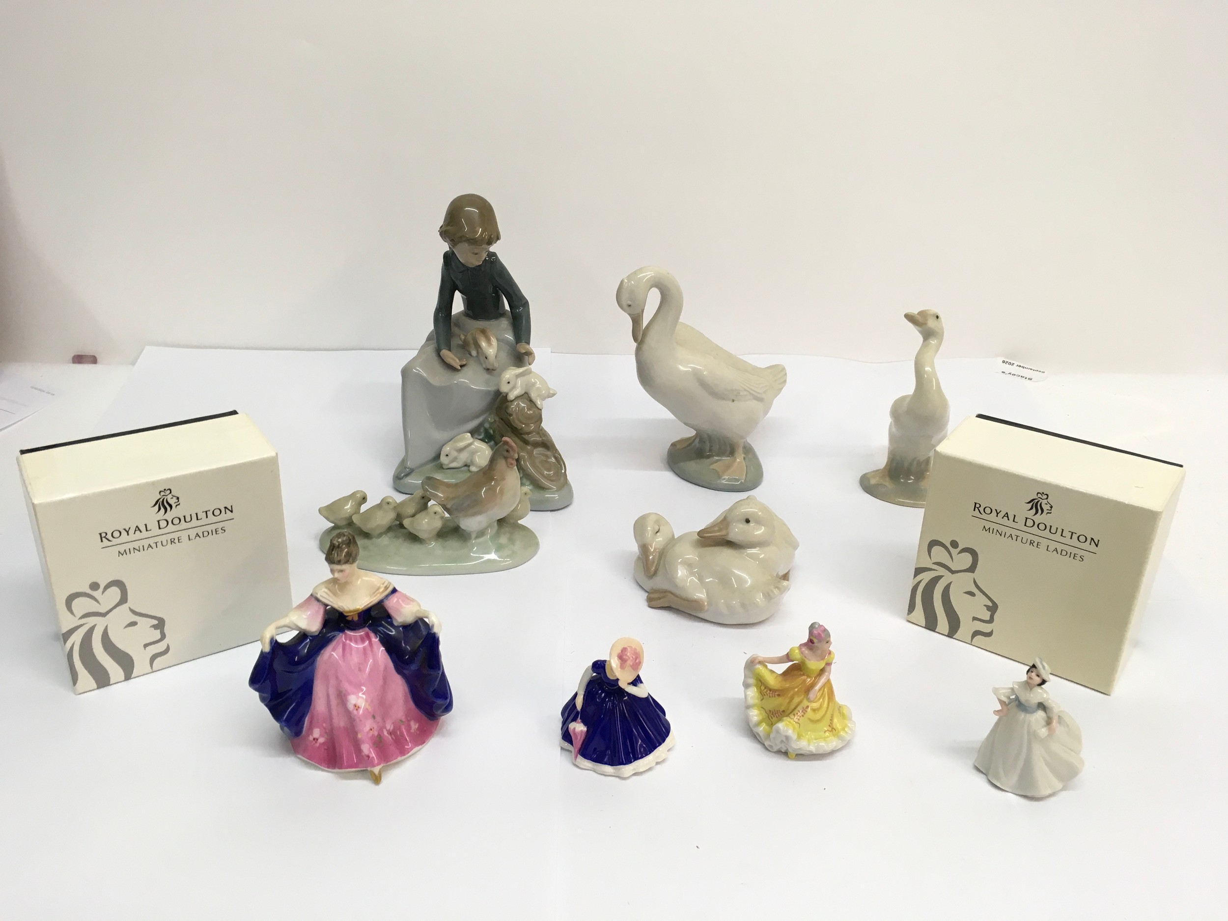 A group of Nao models and Royal Doulton miniature ladies.