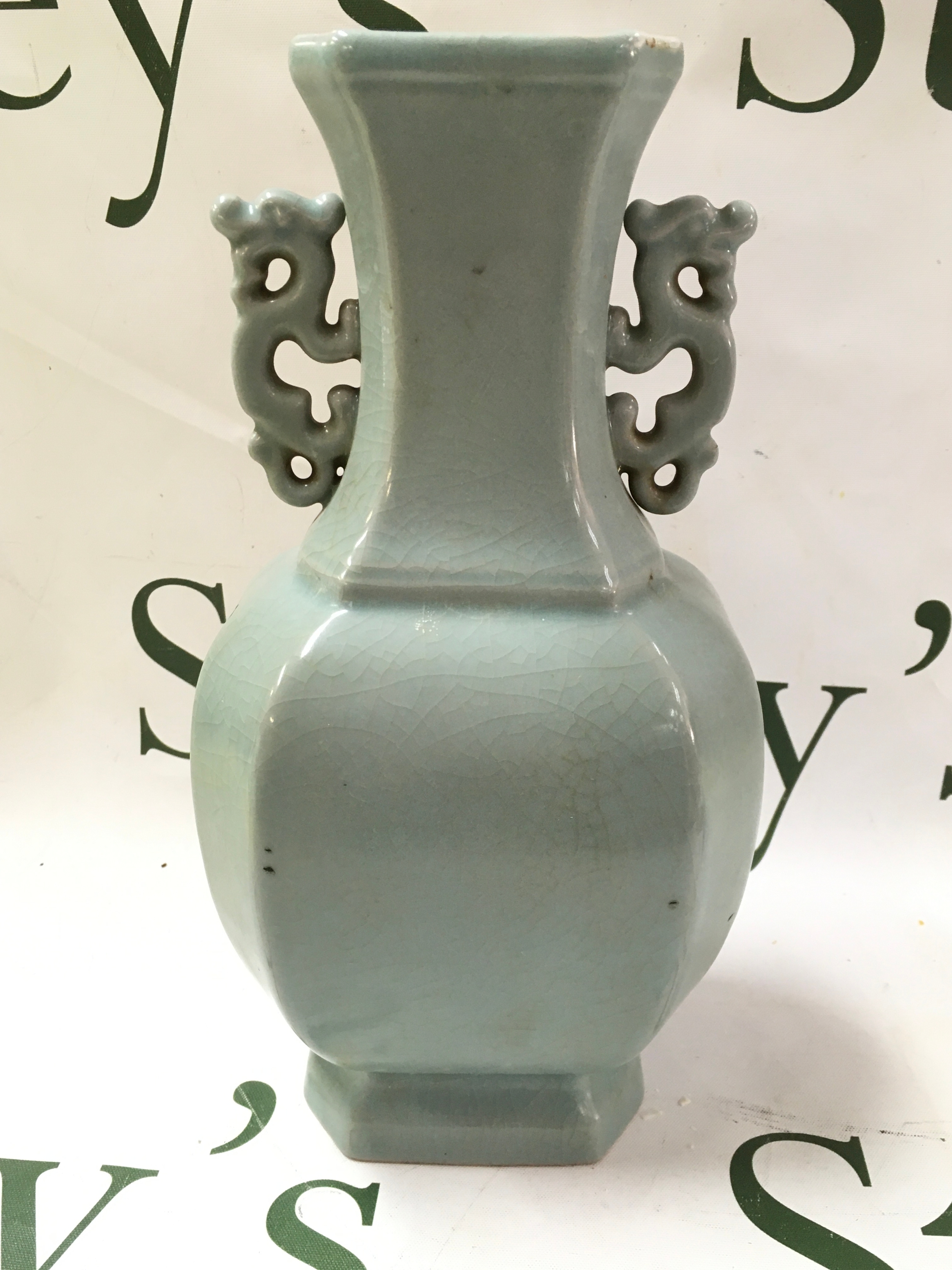 Chinese celadon-glazed porcelain vase featuring a pale blue crackle glaze and twin archaistic pierced handles, 24cm tall