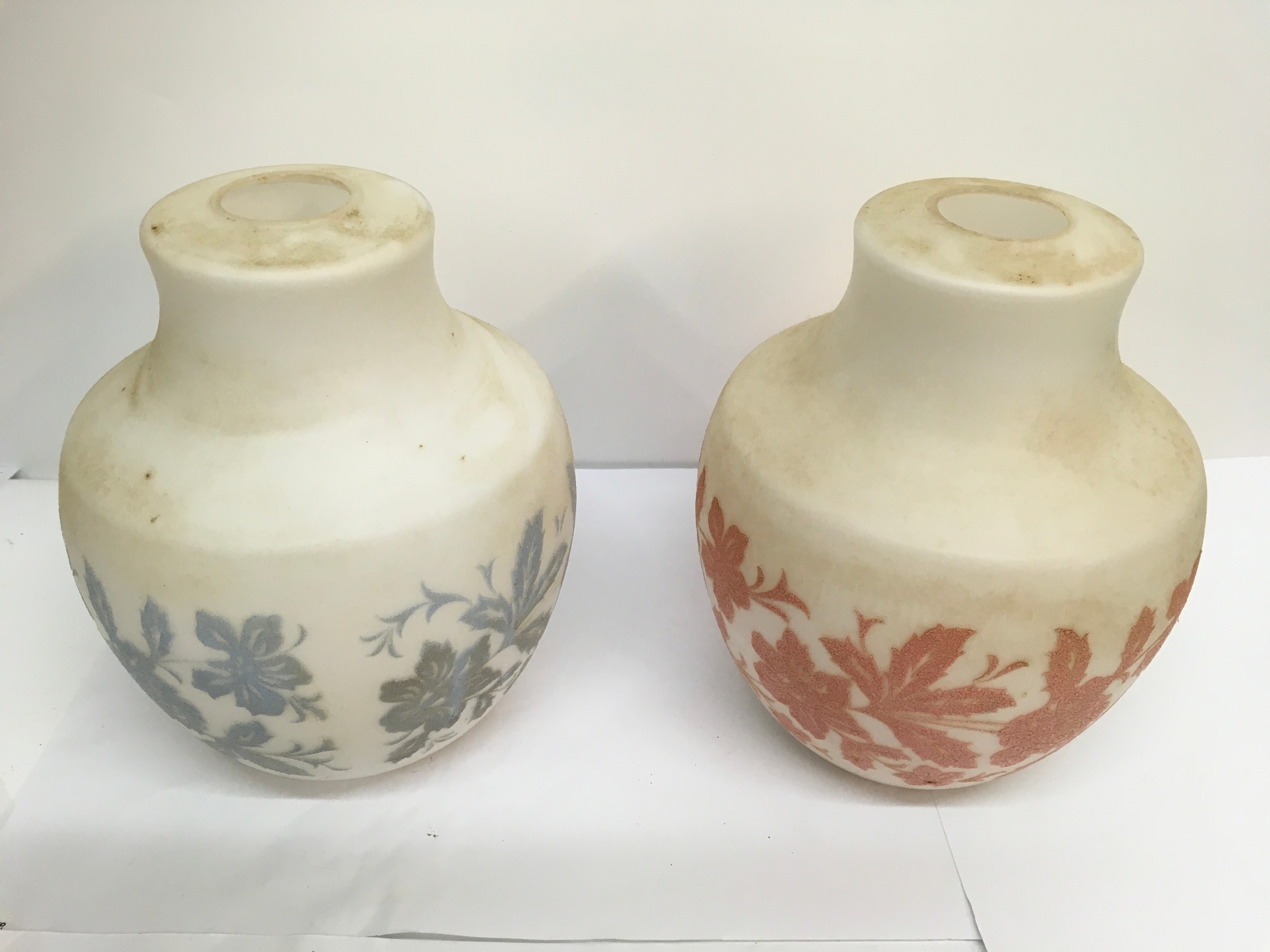 A pair of opaque glass shades relief decorated with coloured floral design. Approx: W13 x H25cm