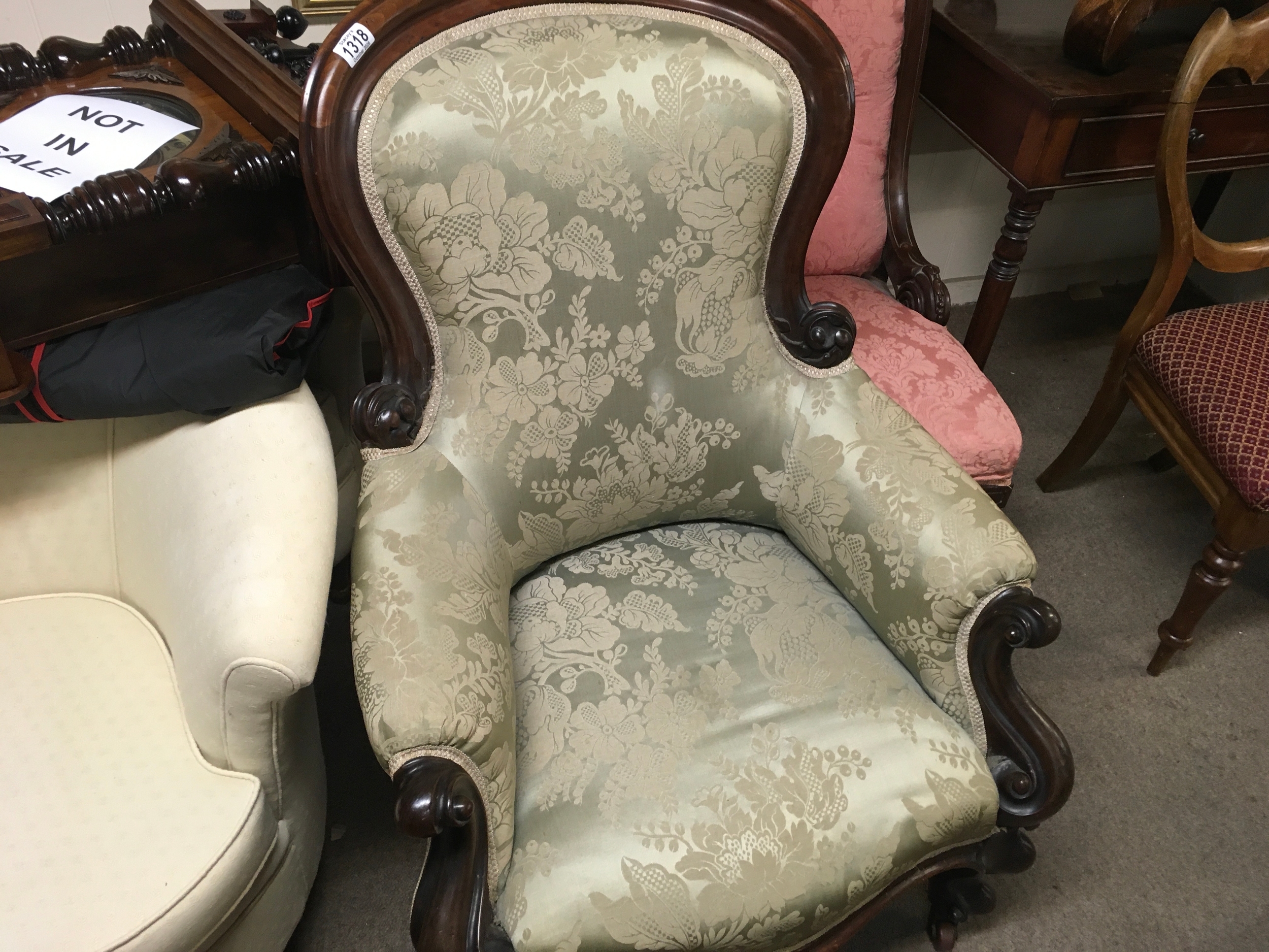 a Victorian mahogany framed armchair, featuring an elegant curved wooden frame and green floral upholstery