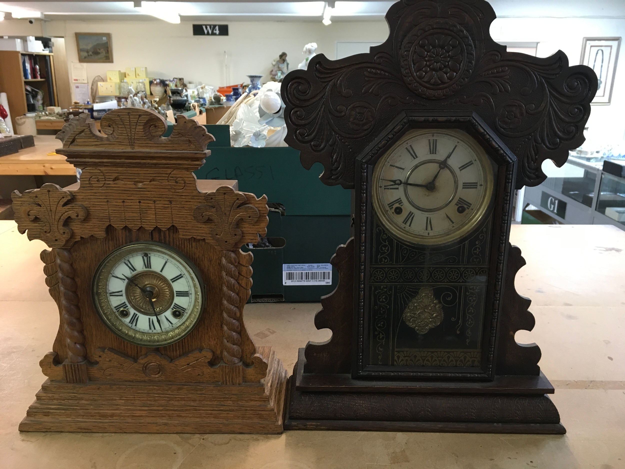 An antique oak shelf/mantel clock featuring a pressed wood case with rope-twist pillar accents and a dark-stained wood or oak gingerbread clock with elaborate press-carved leaf and scroll motifs