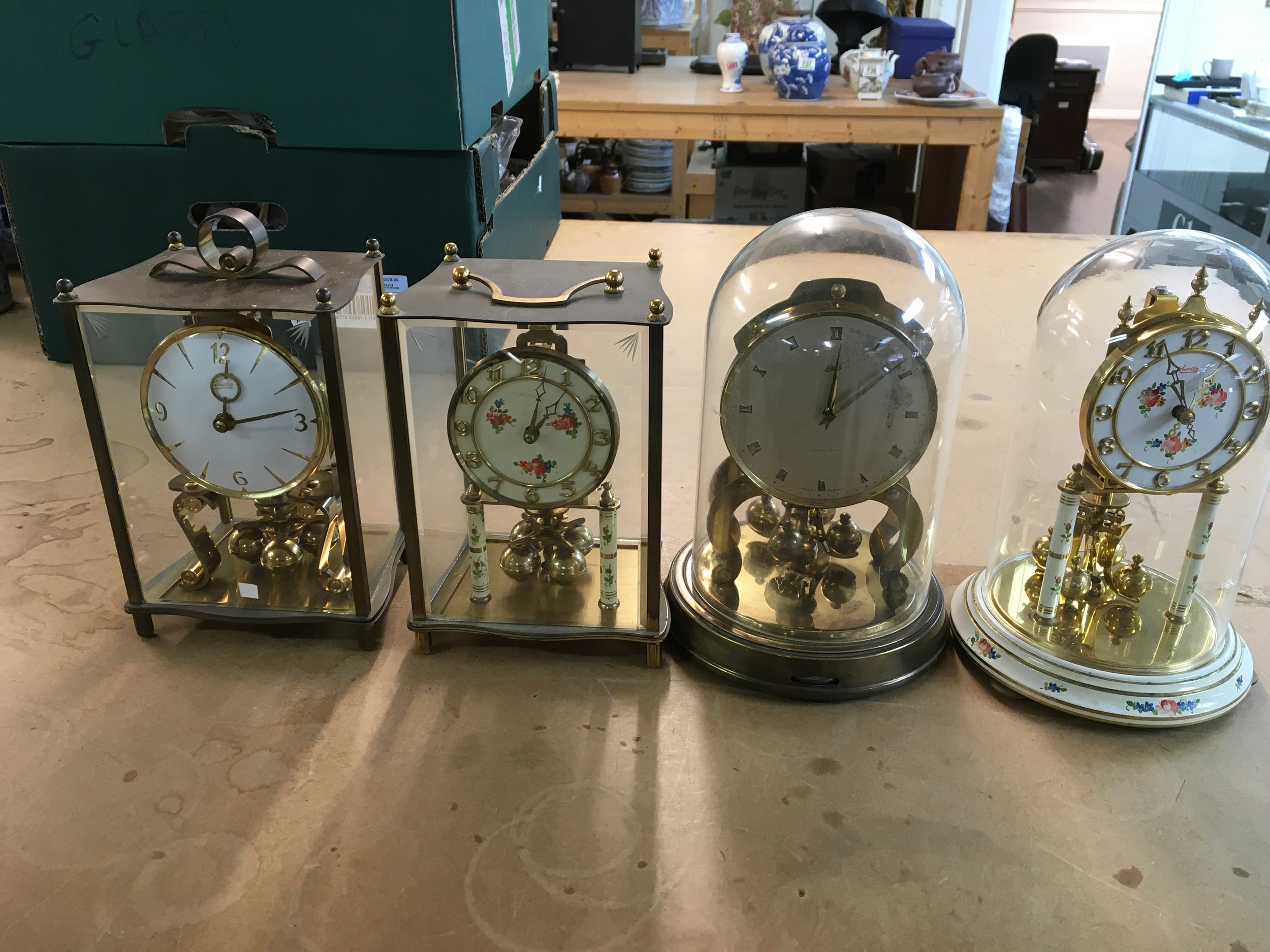 Collection of four mantle clocks including vintage Kundo four-glass brass torsion anniversary clock and vintage Kundo 400-day torsion anniversary clock.