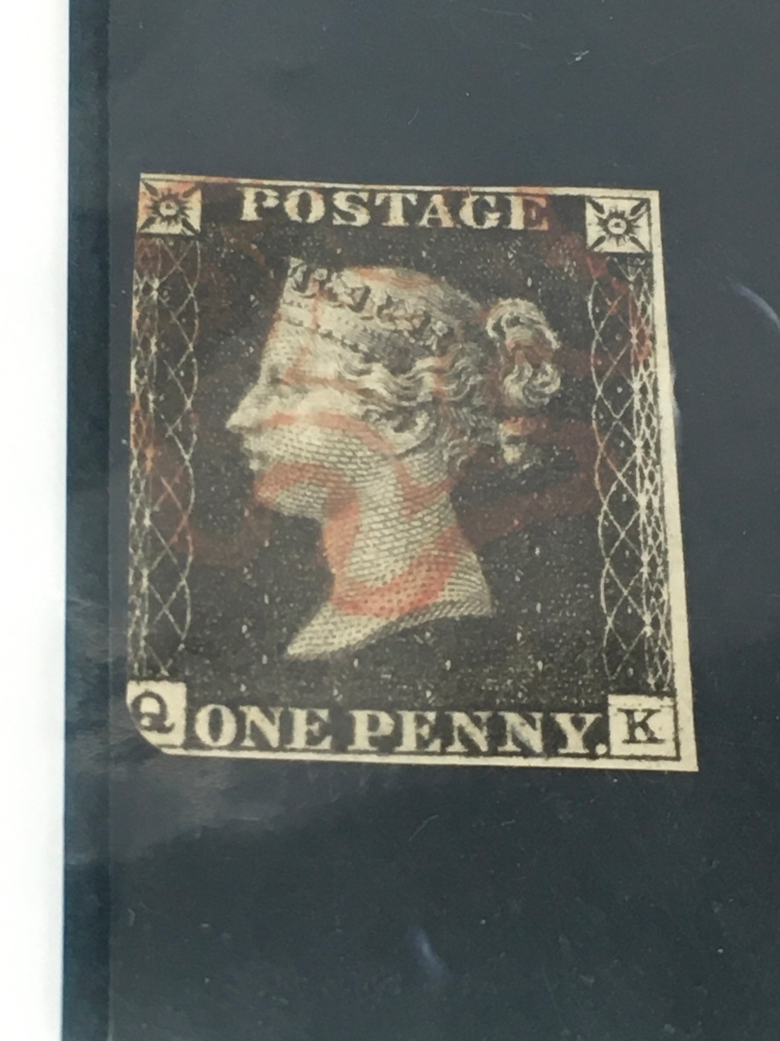 1840s Queen Victoria One Penny Black postage stamp featuring a profile of Queen Victoria and a red Maltese Cross cancellation. QK letters, in good used condition.