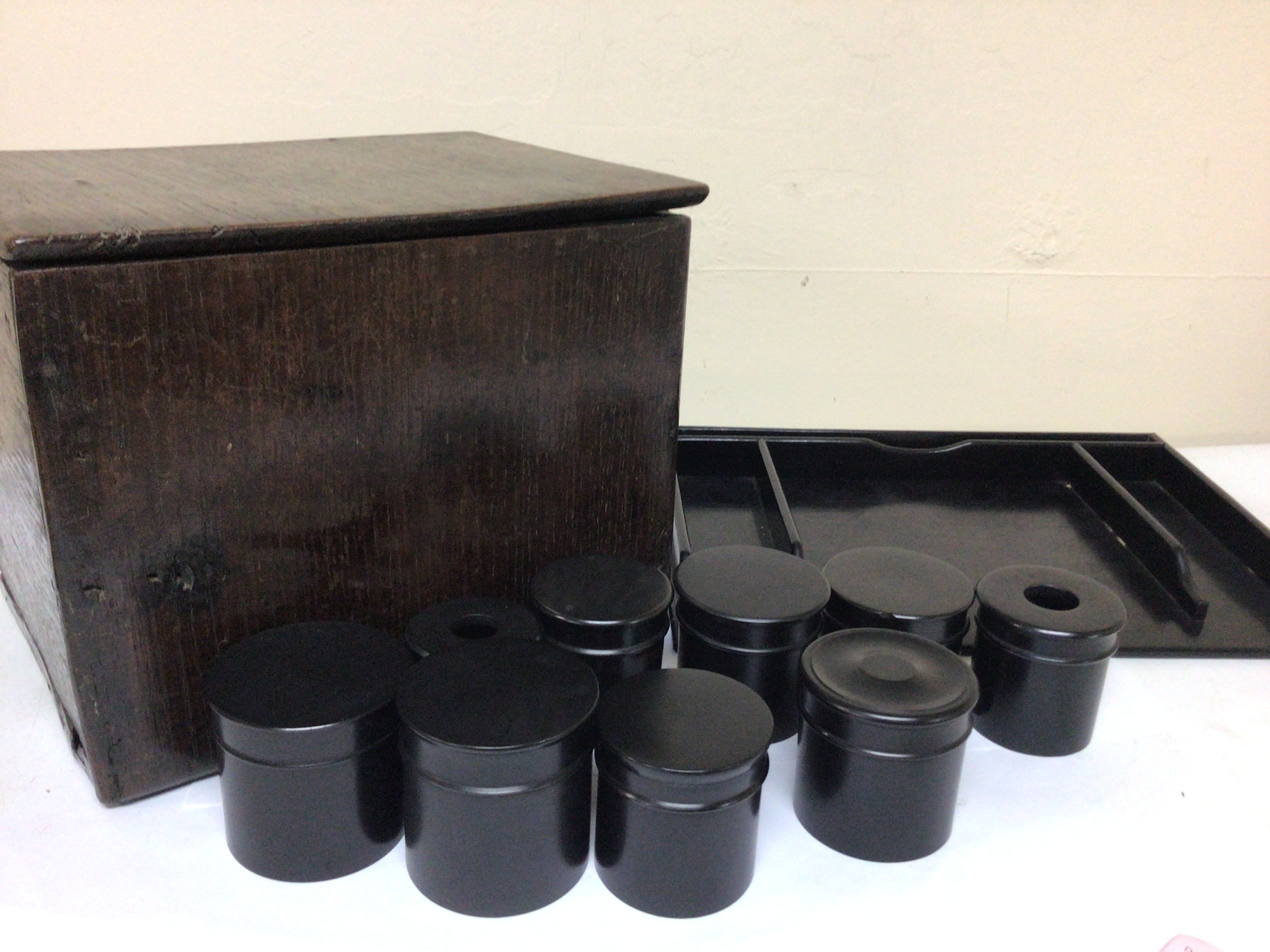 A collection of ebony wood pots with lids a tray and an oak vernacular 19th century storage box containing door fittings and oddments. NO RESERVE