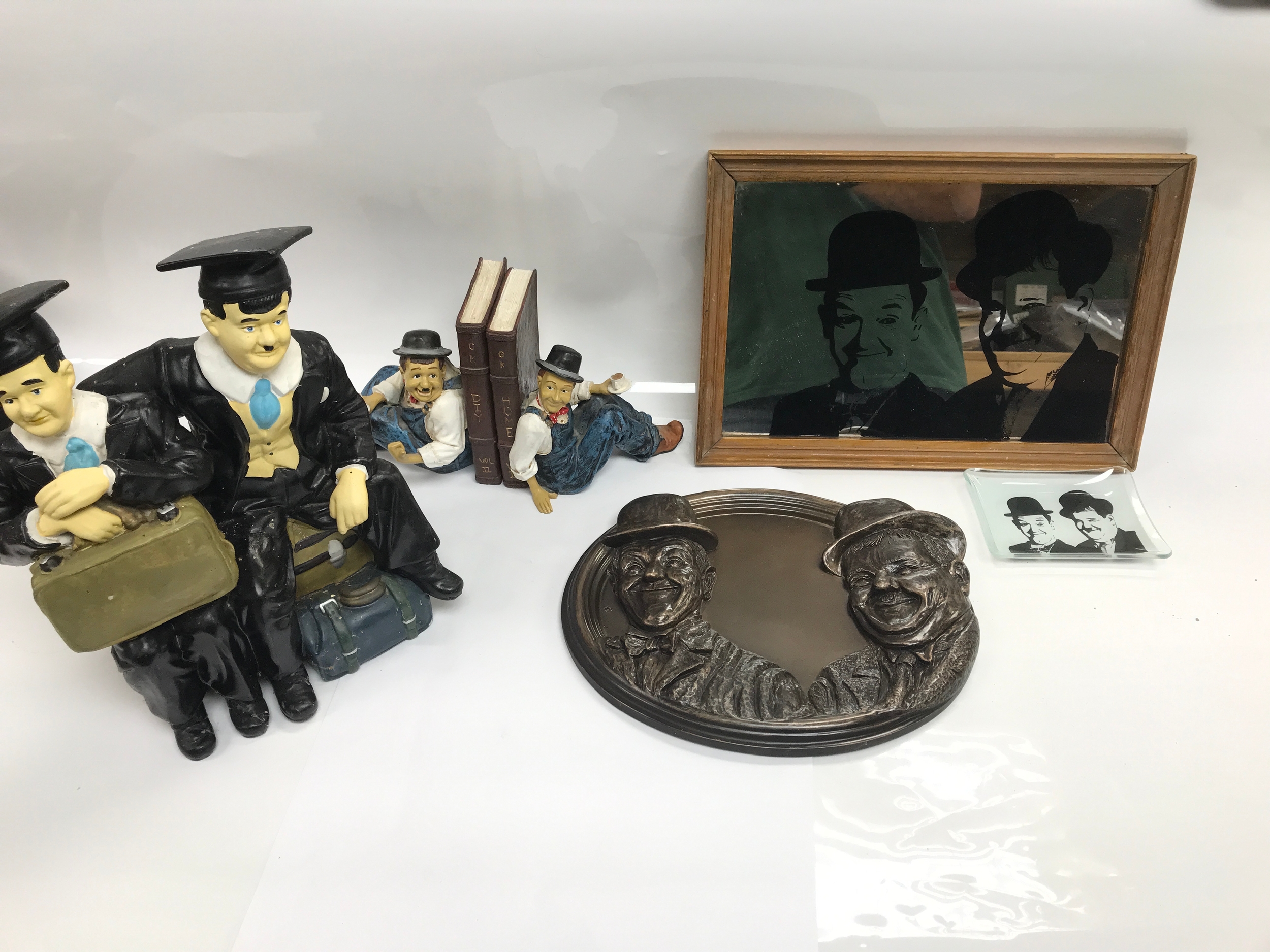 Collection of Laurel and Hardy items including oval wall plaque with sculpted likenesses of Stan Laurel and Oliver Hardy in their iconic bowler hats, book ends, mirror etc