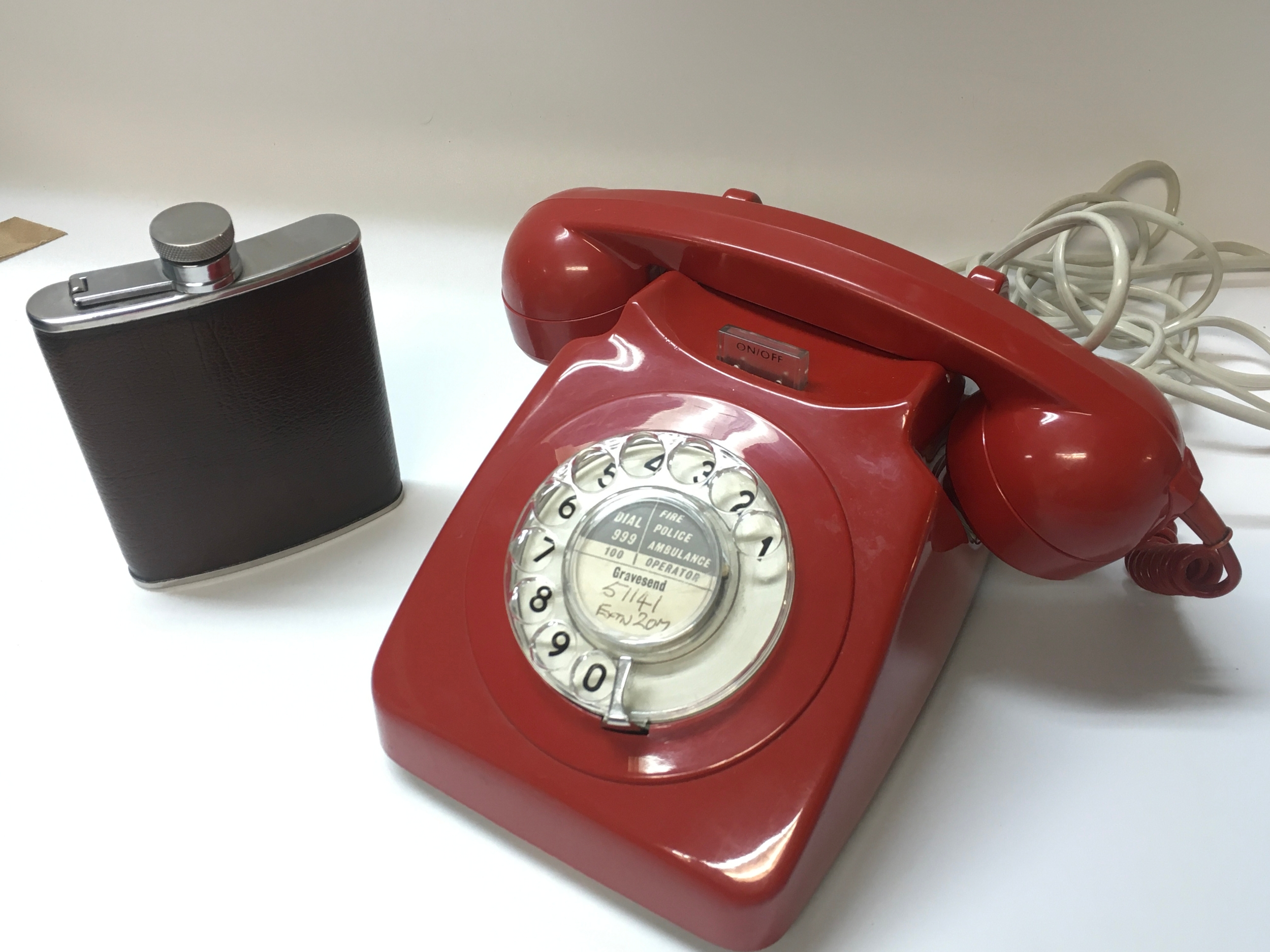 A vintage red telephone and a hip flask